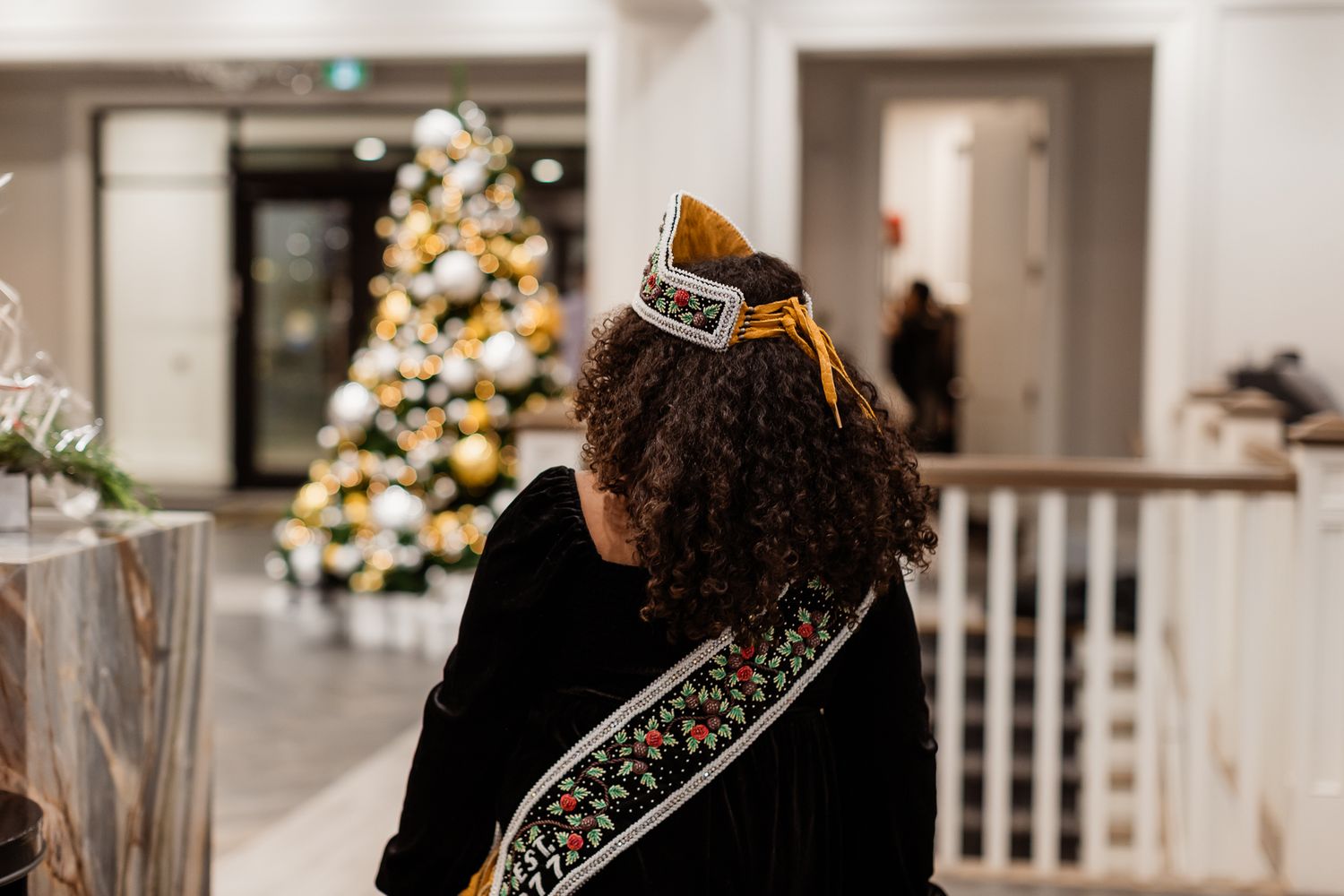 Elegant Christmas decorations and white picket fencing adorn an indoor space.