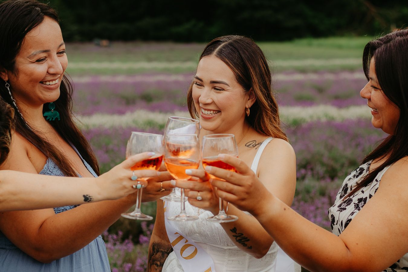 Group toasting with drinks at outdoor celebration surrounded by lavender flowers.