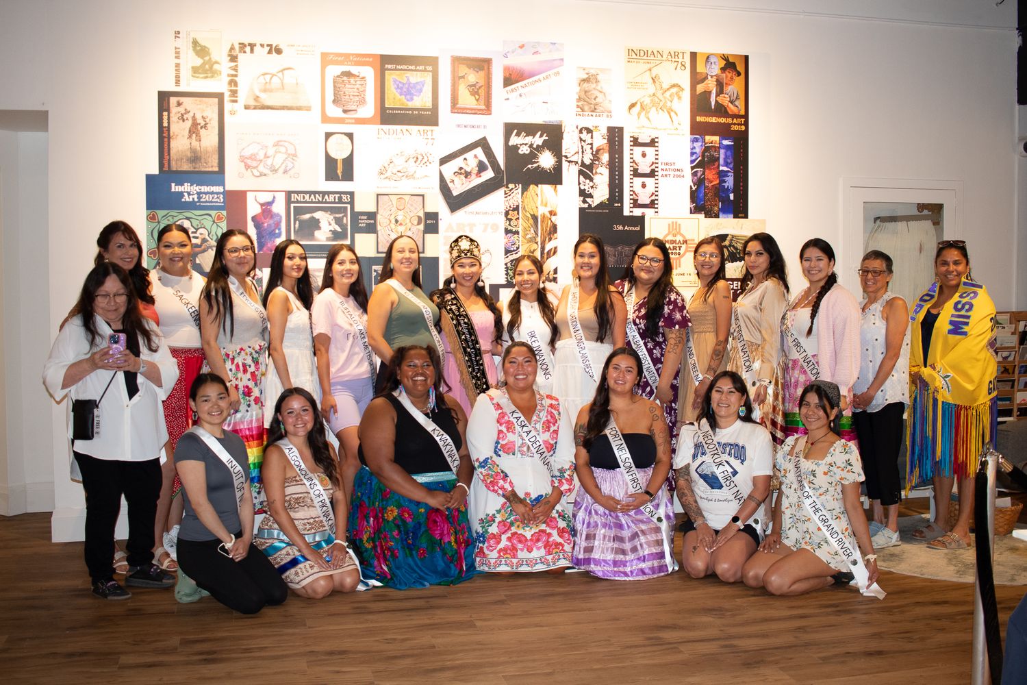 Large group photo of event participants posing against a wall with artwork.