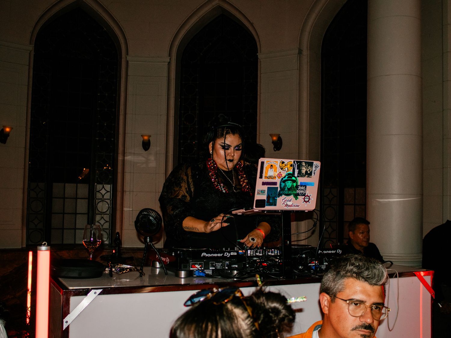 Female DJ performing at turntables in dark venue with Pioneer DJ equipment.