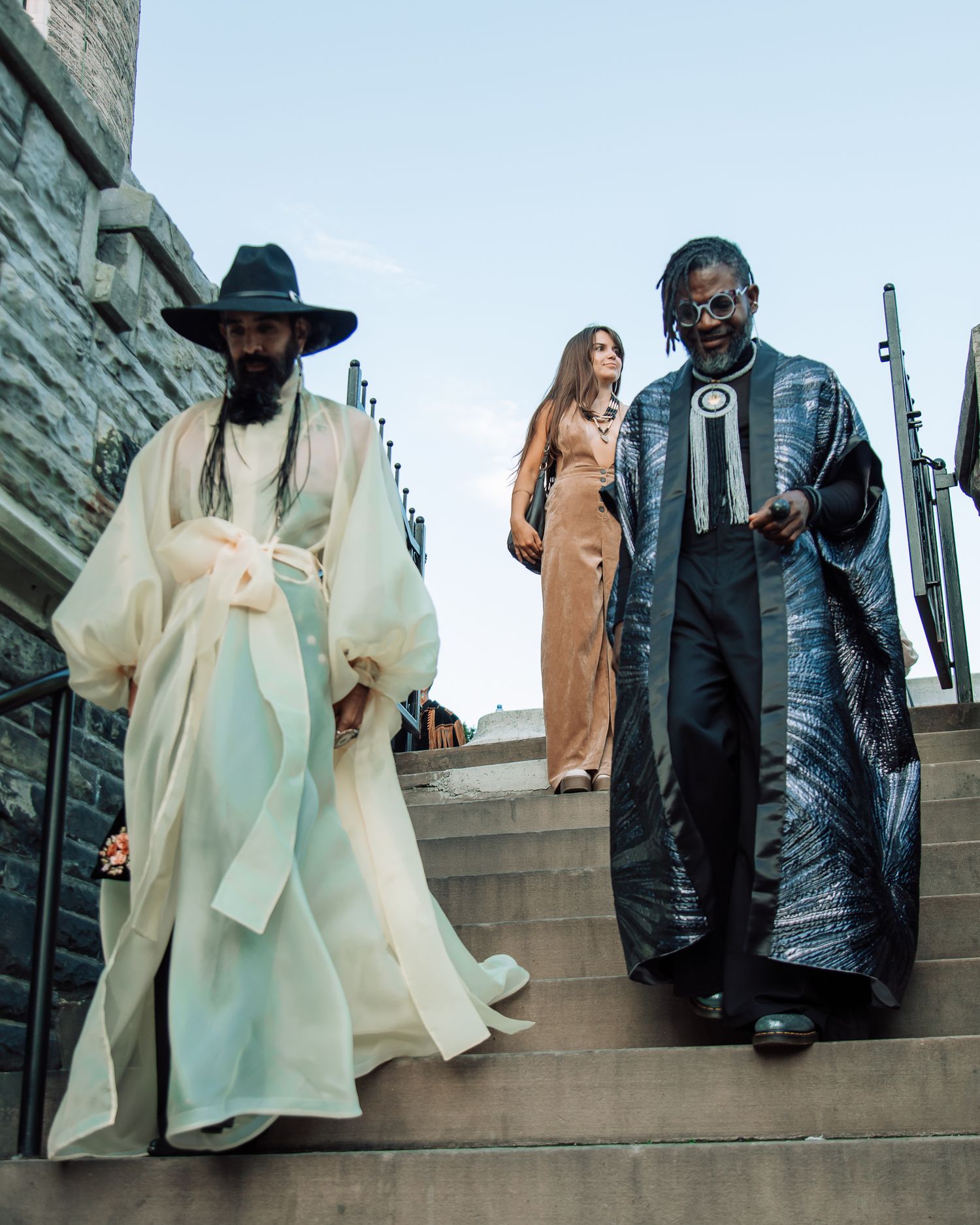 People in contrasting light and dark outfits pose on concrete steps during an artistic photoshoot.