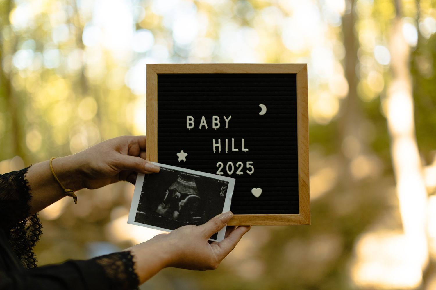 Small chalkboard signs photographed outdoors announcing a baby due in 2025.
