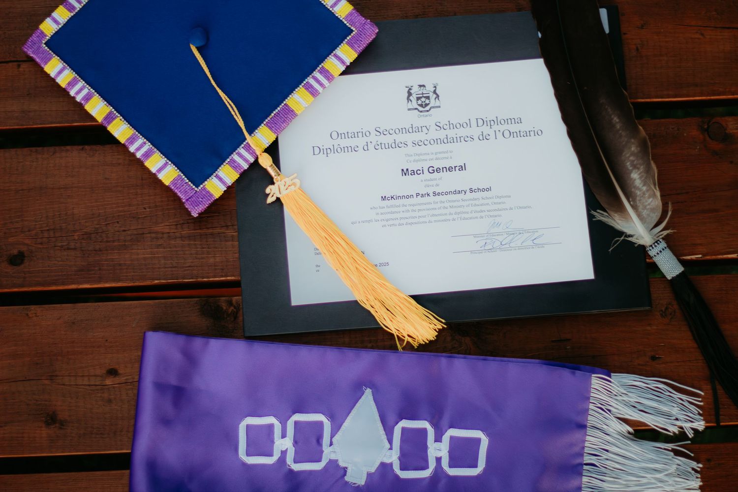 A graduation diploma and decorative sash displayed on a wooden surface.