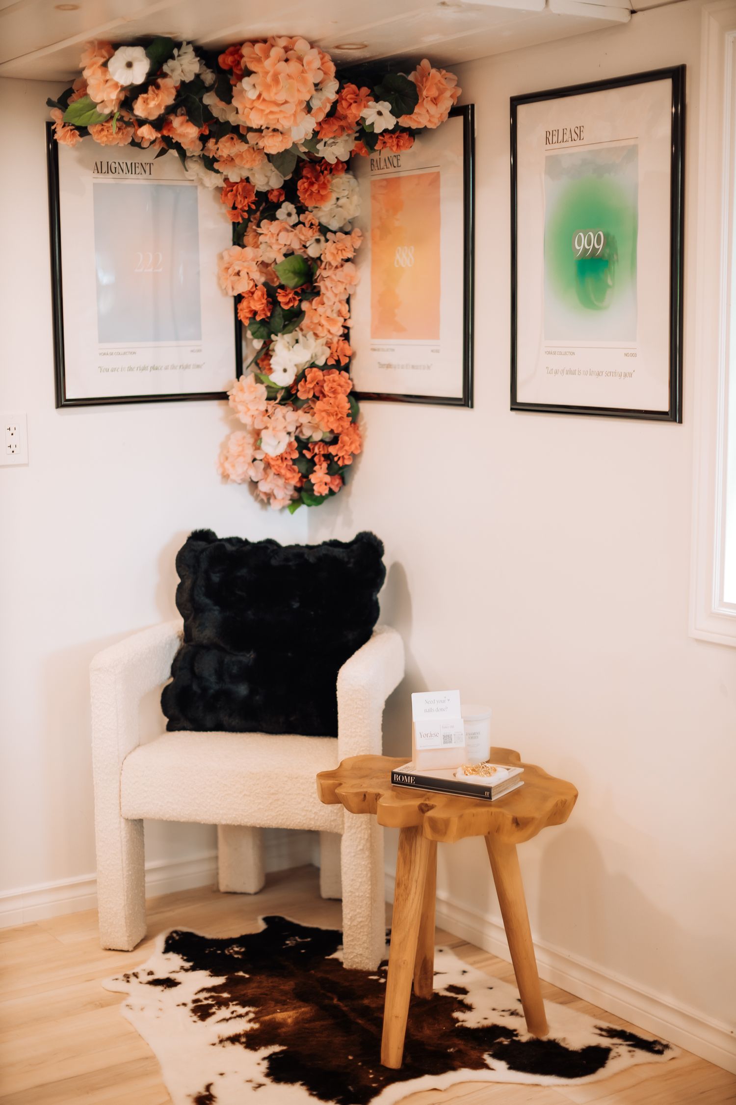 Cozy nail salon waiting area with wooden stools and decorative floral arrangements.