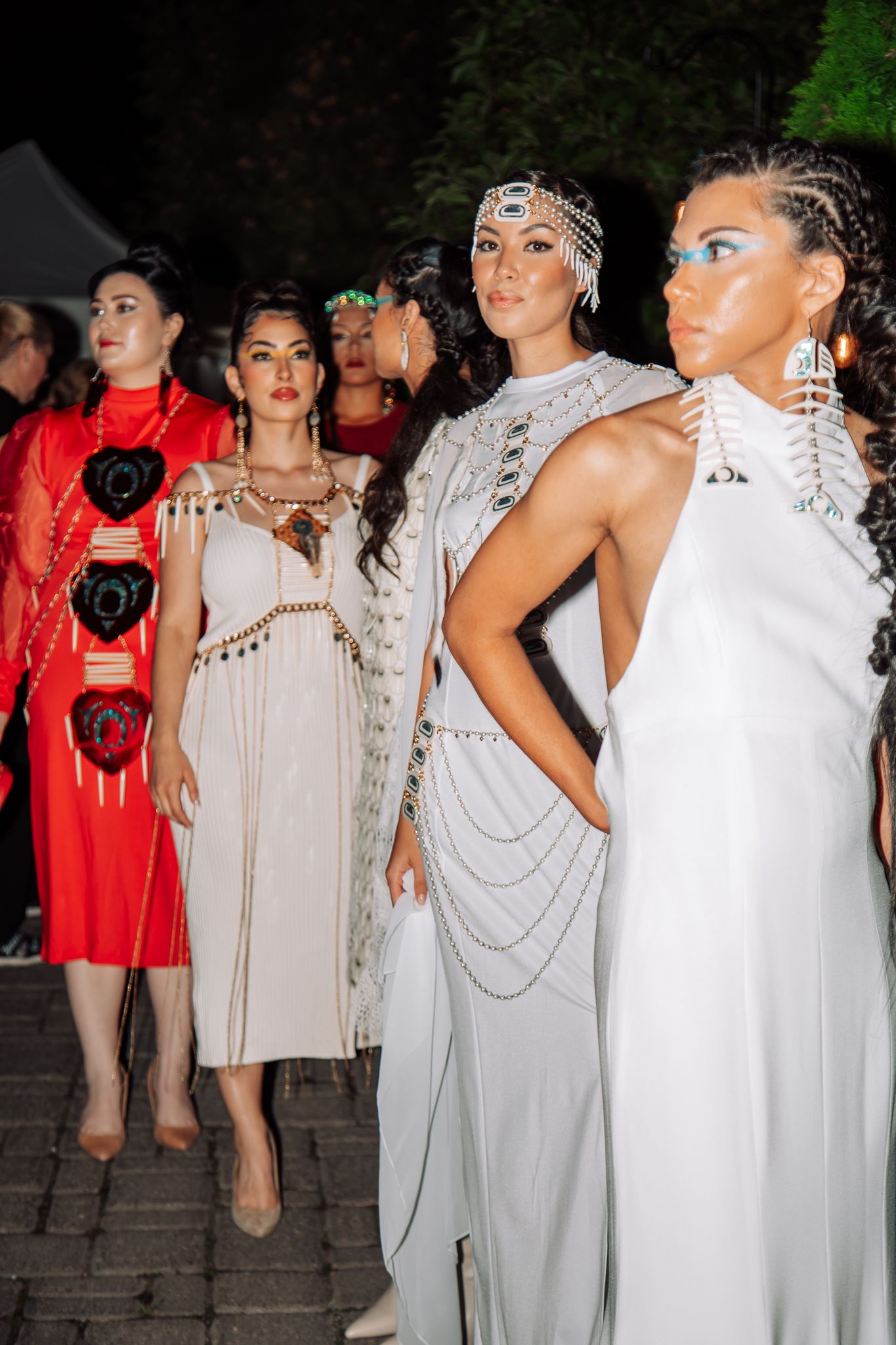 Fashion models lined up wearing coordinated white and red ensembles on stone steps.