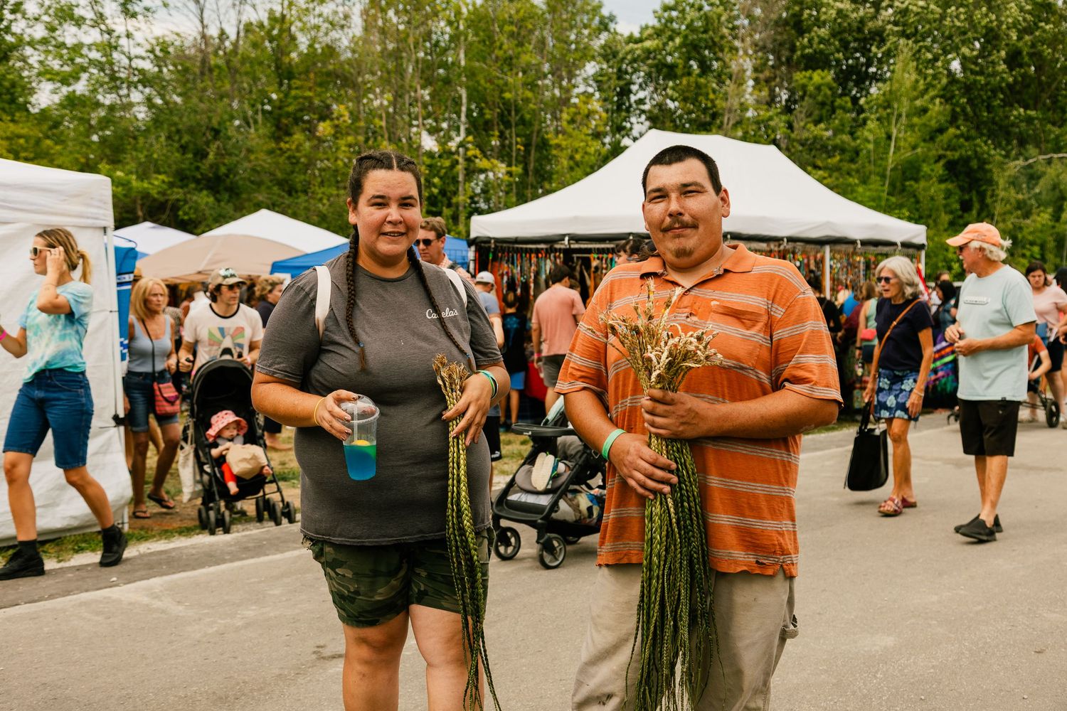 Festival attendees gather under white tents at an outdoor cultural celebration.