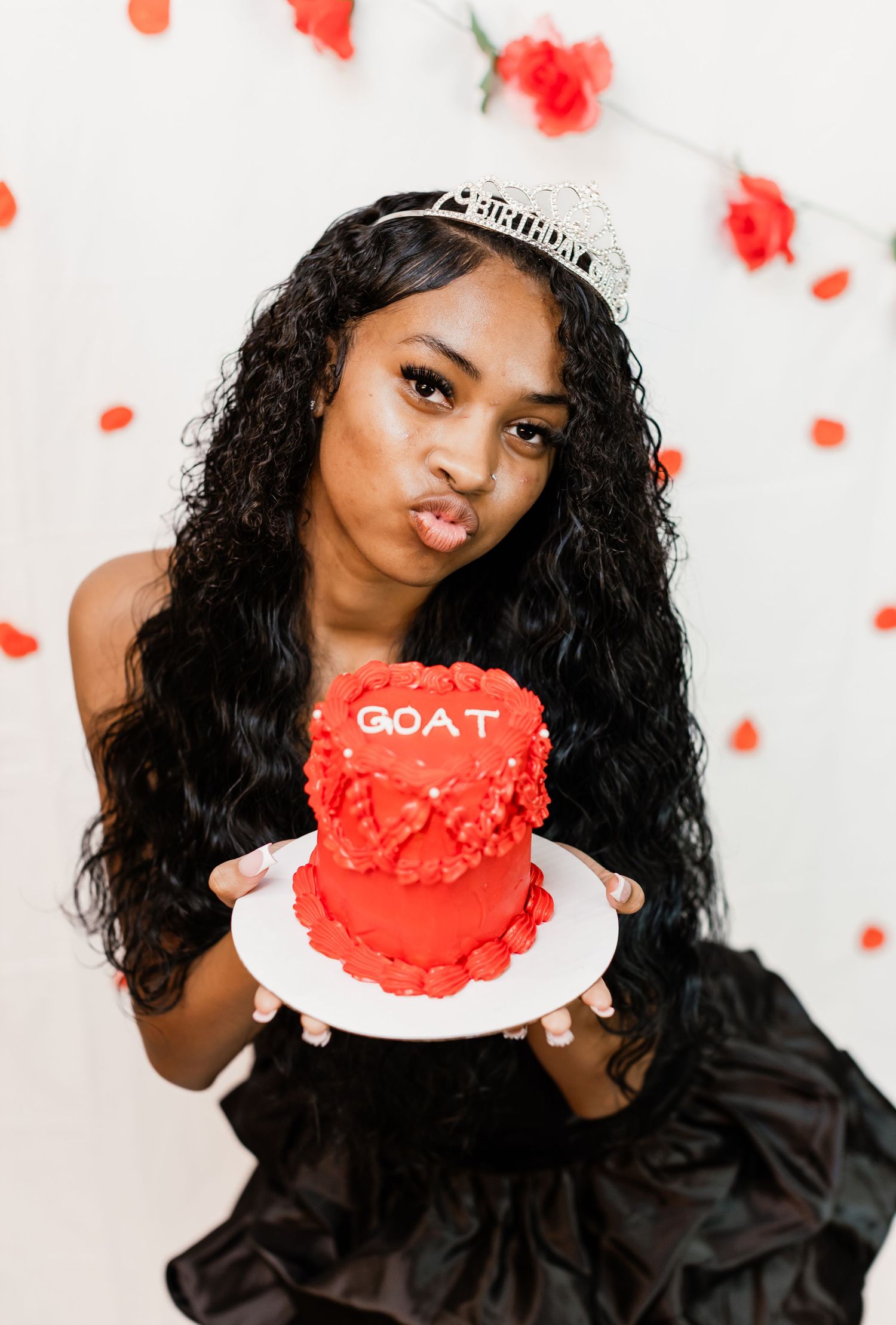 Stylish celebration photo featuring a red frosted cake with 'GOAT' text.