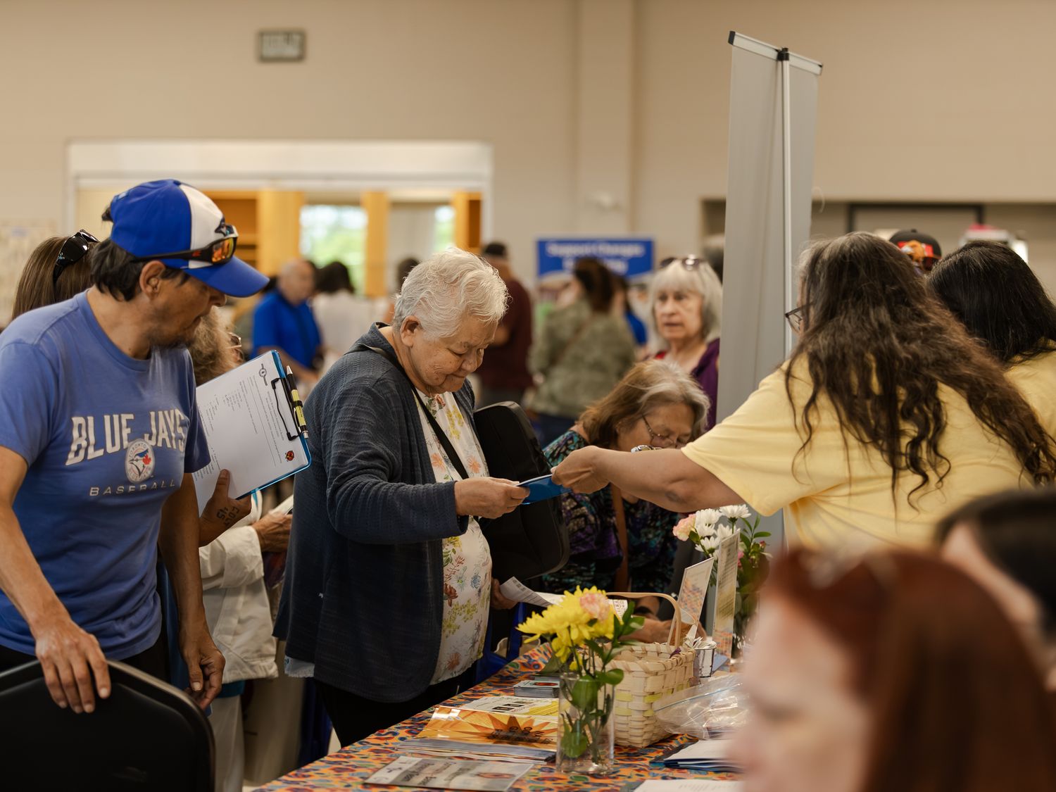 Diverse group of people browsing and interacting at an indoor community health fair event.