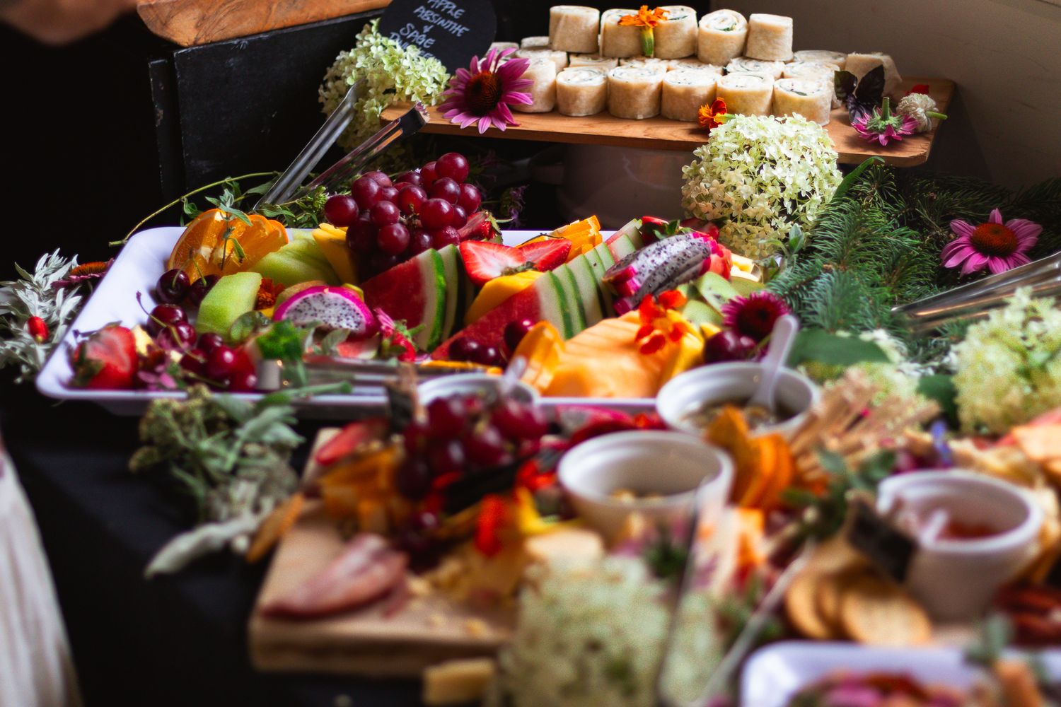 Elaborate charcuterie board with fresh fruits, meats, cheeses and appetizers beautifully displayed.