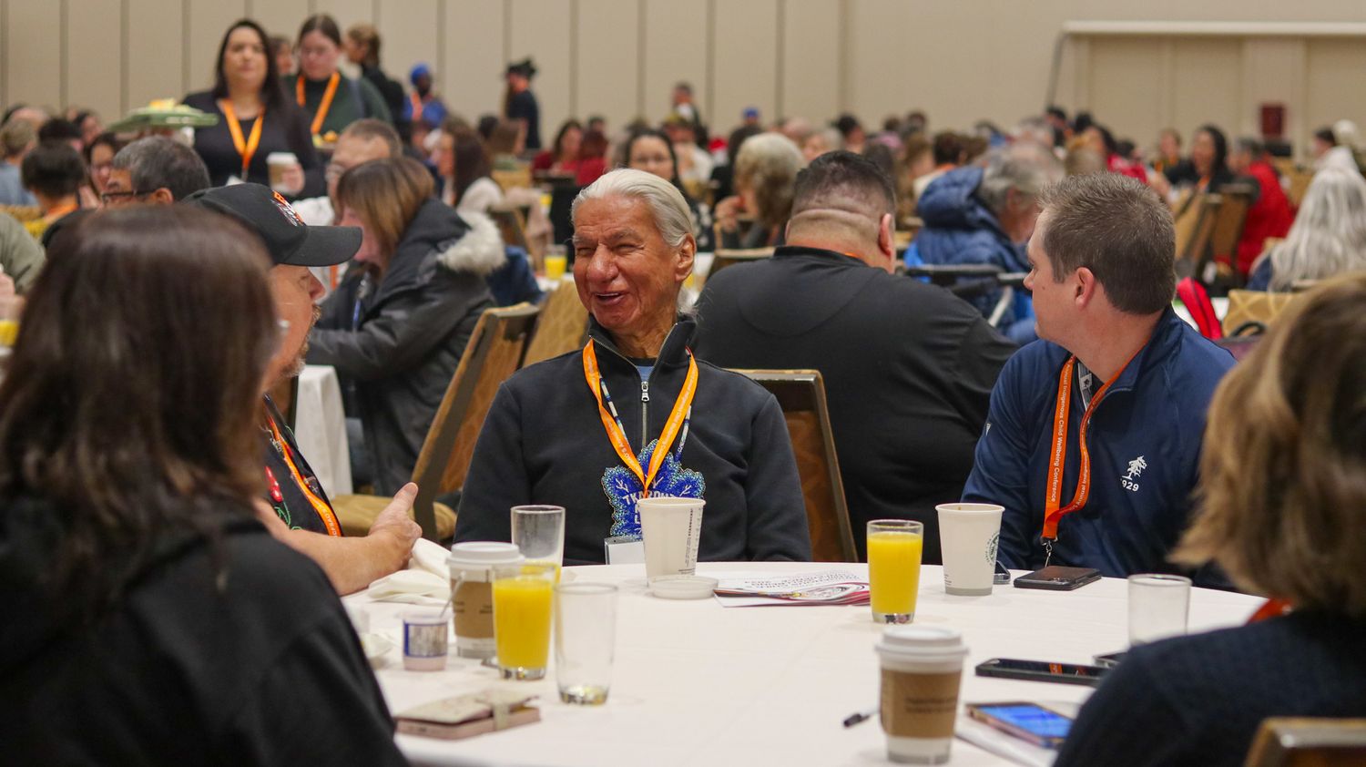 Conference attendees seated at round tables in a large meeting room during a professional event.
