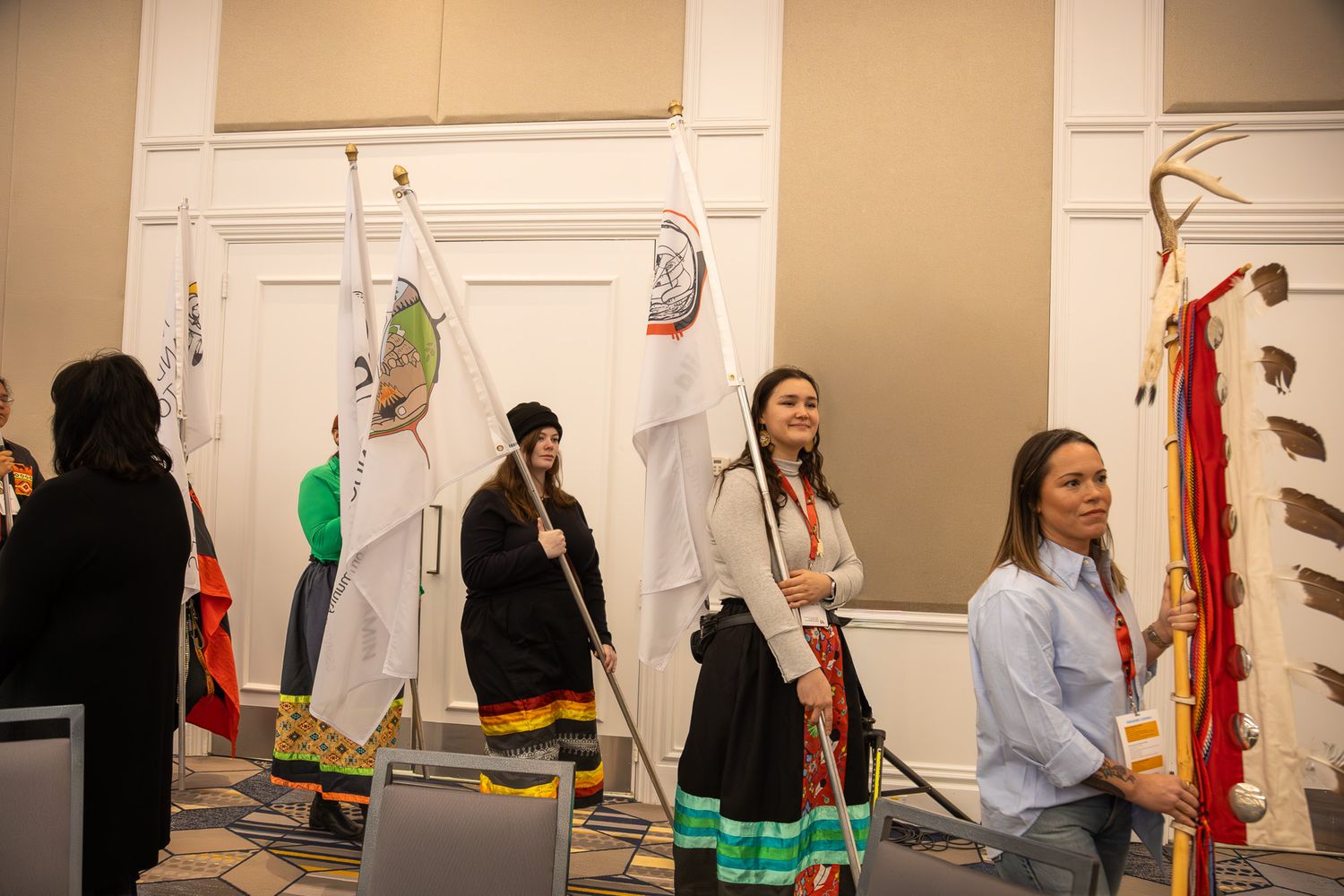 Event participants standing near a white wall with hanging decorative items.