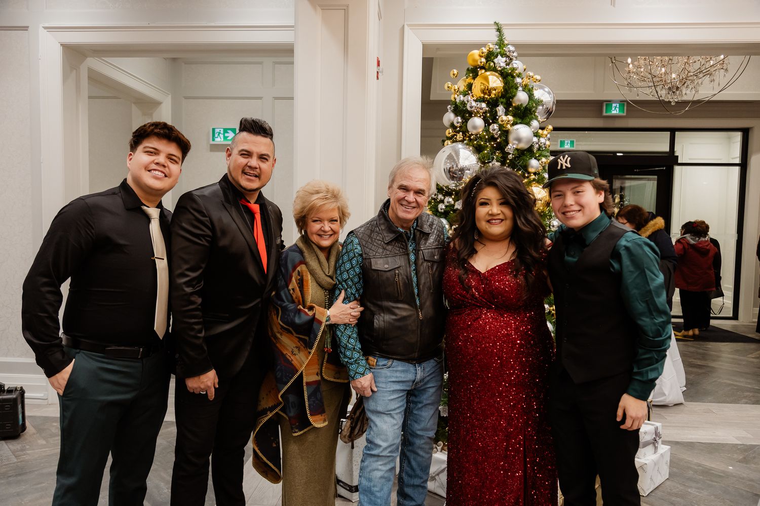 Group photo at a holiday party with a decorated Christmas tree in the background.