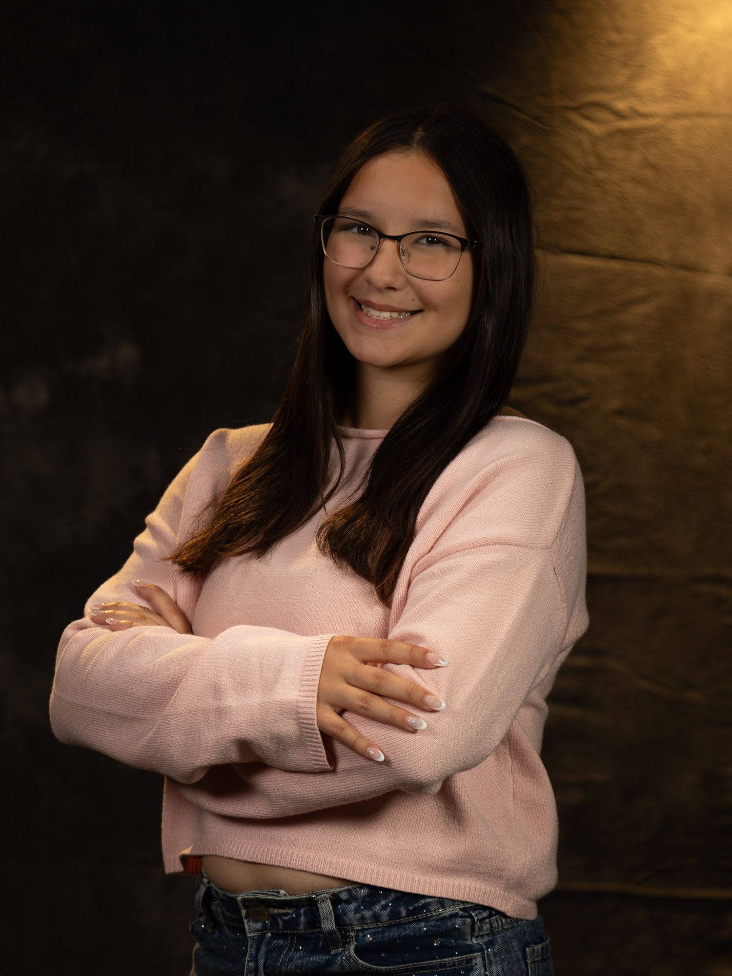 Studio portraits showing someone in a pink sweater and jeans against a dark backdrop.