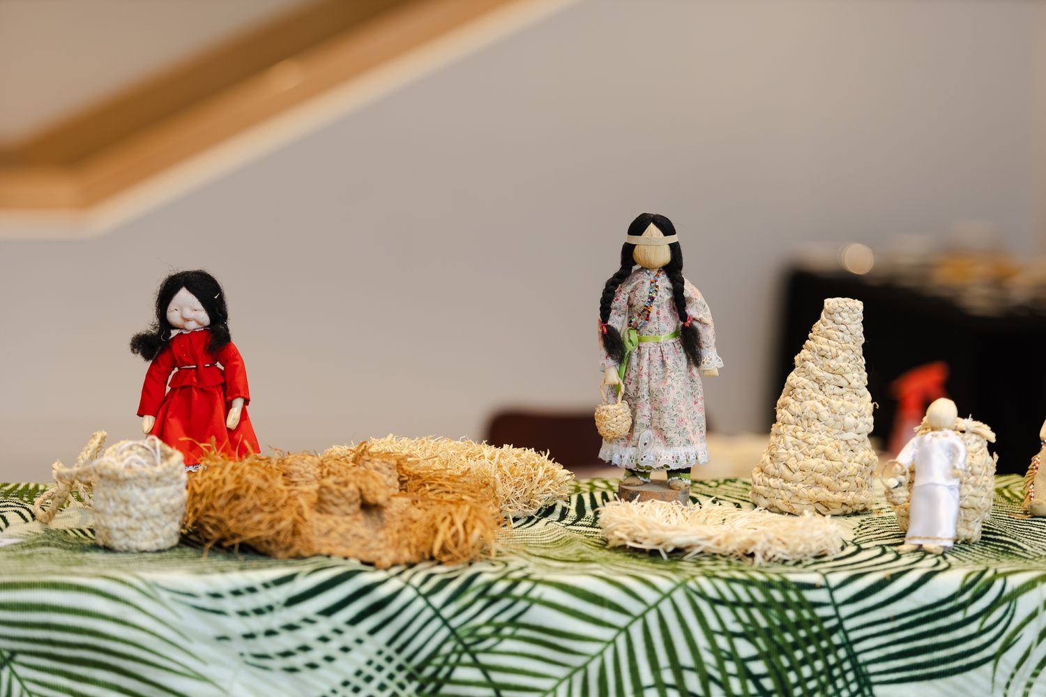 Handmade Native American corn husk dolls displayed on a green leaf tablecloth.