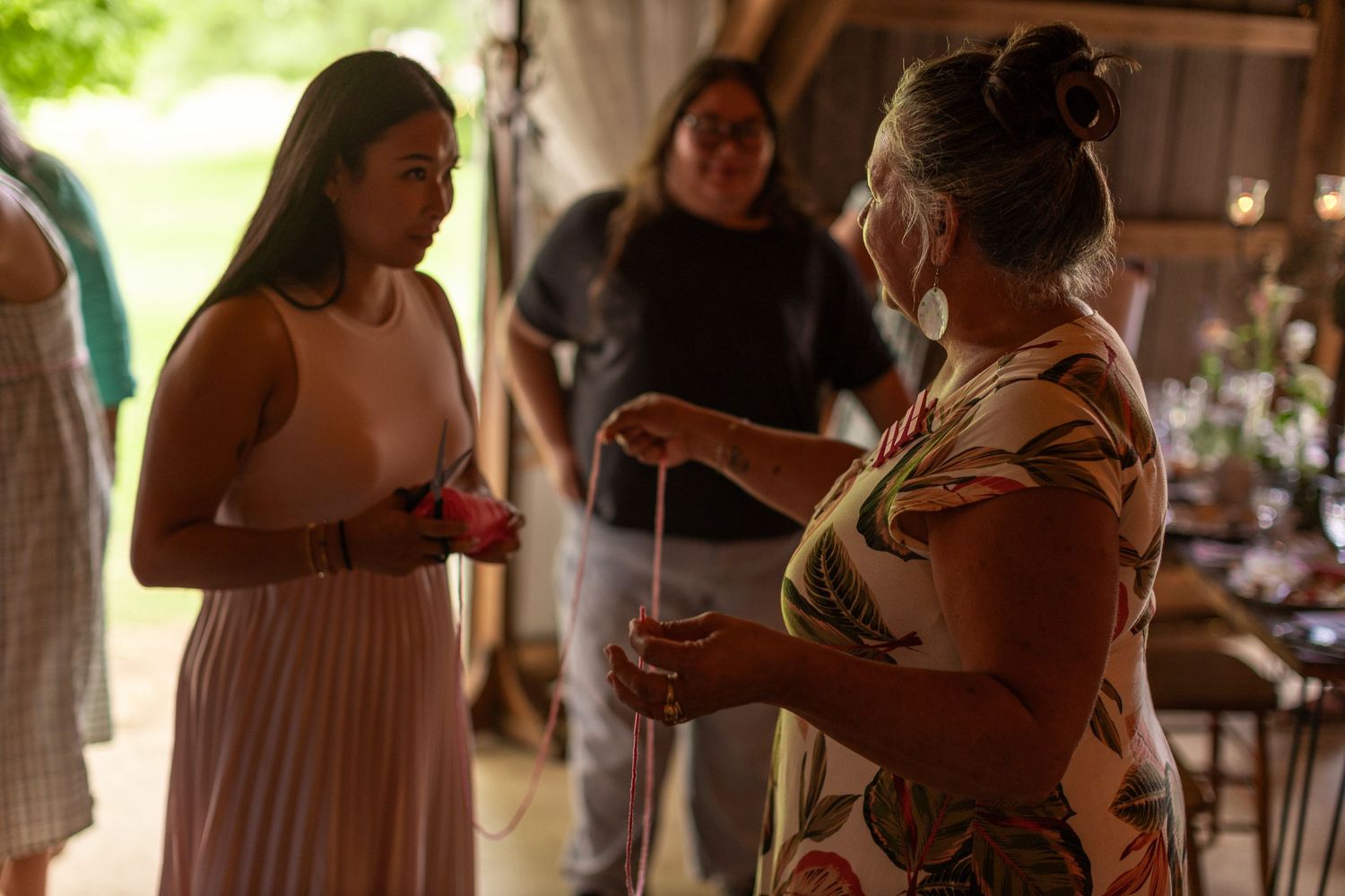 Wedding party members in pink and neutral dresses socialize during an outdoor celebration.