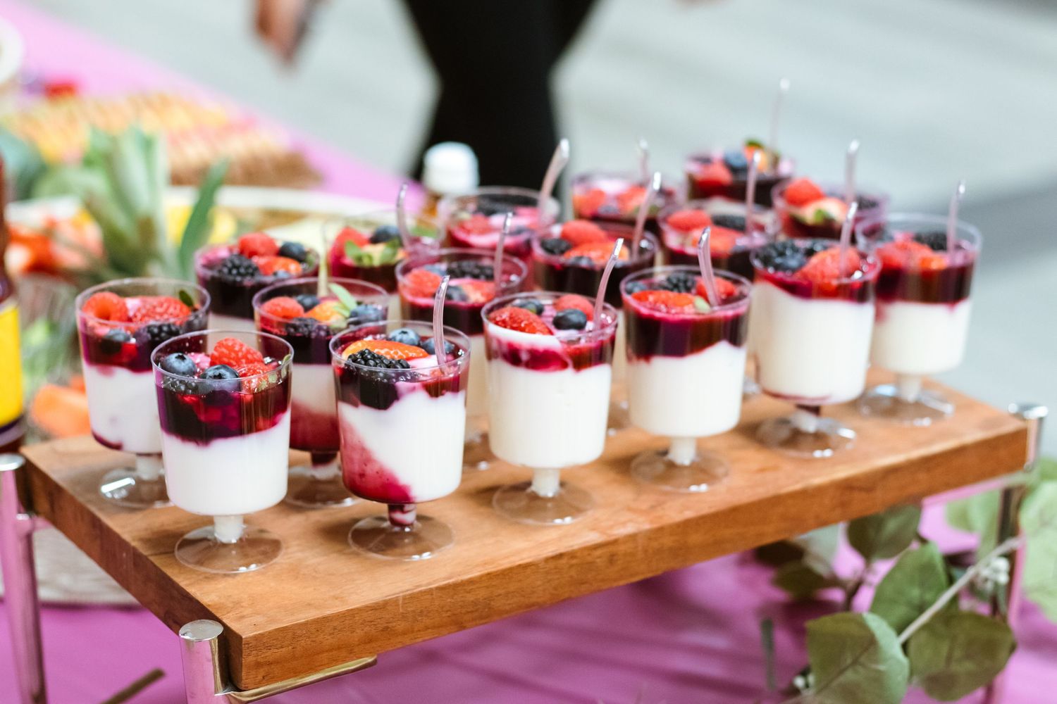 Wooden board displaying individual berry parfait desserts with fresh fruit toppings.