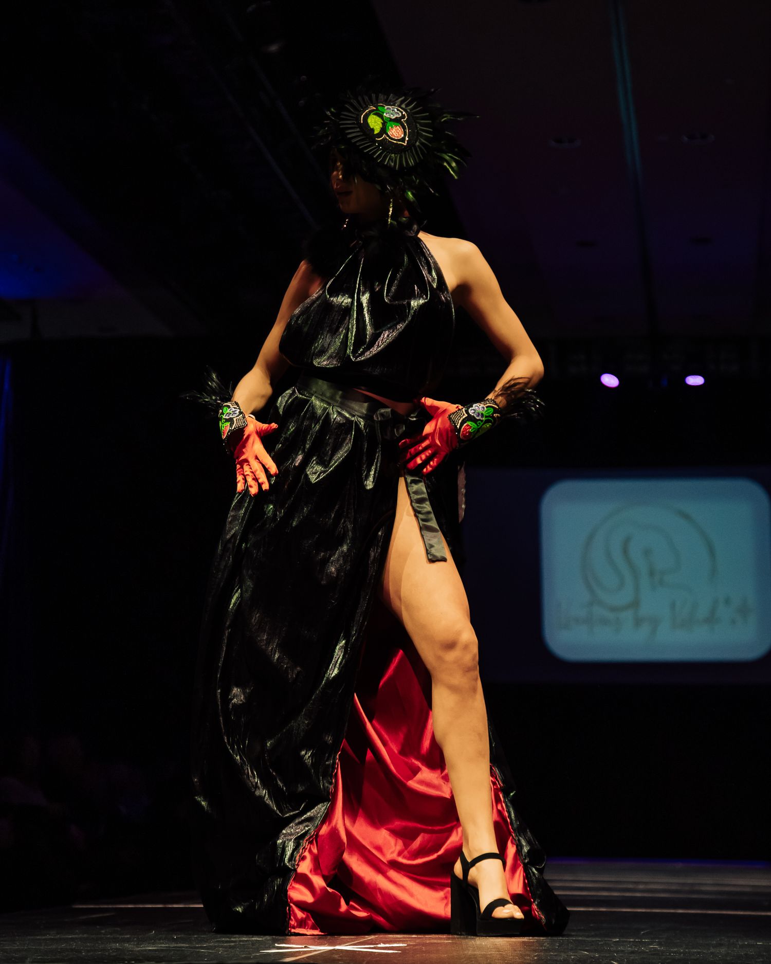 Dramatic dance performance featuring red and black costume on dimly lit stage.
