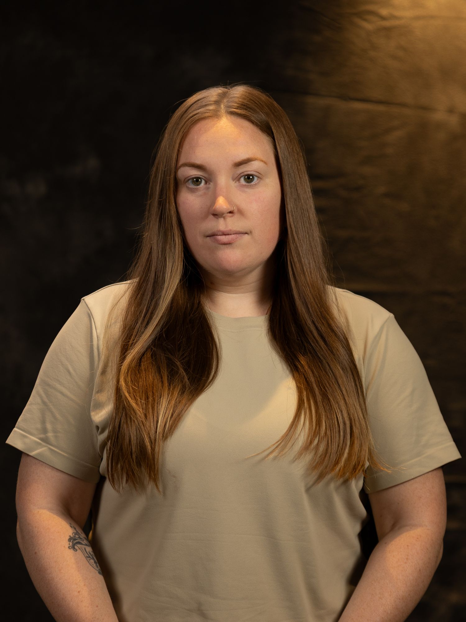 Studio portraits showing someone in a beige t-shirt against a dramatic dark backdrop.