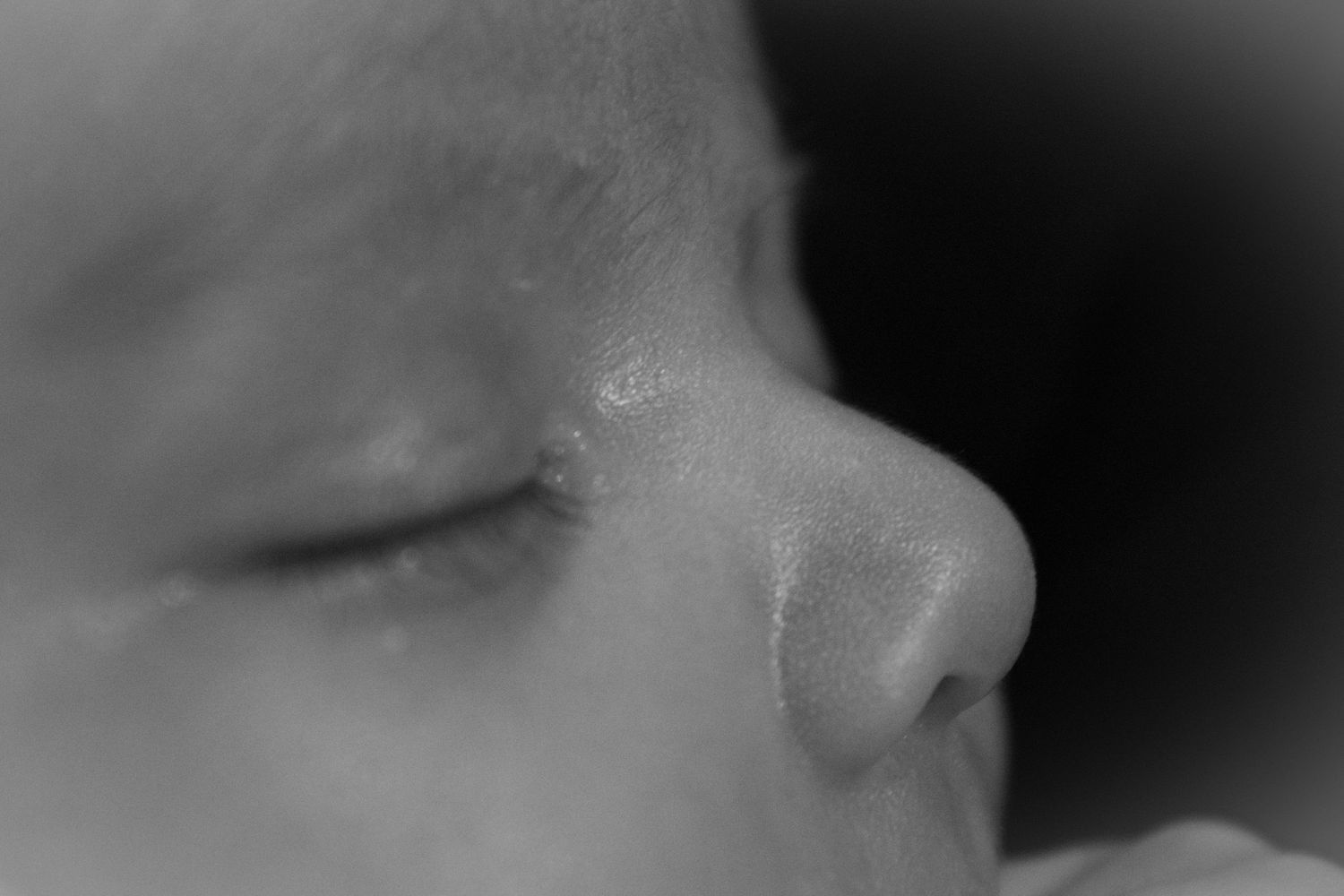 Serene close-up of sleeping baby's features in soft monochrome tones.