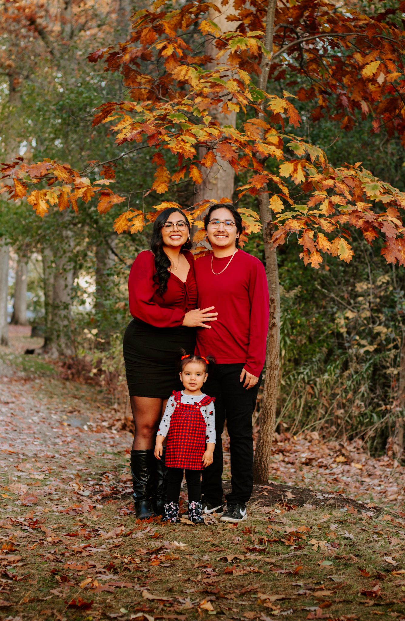 Family autumn portrait with fall foliage and coordinated red outfits.