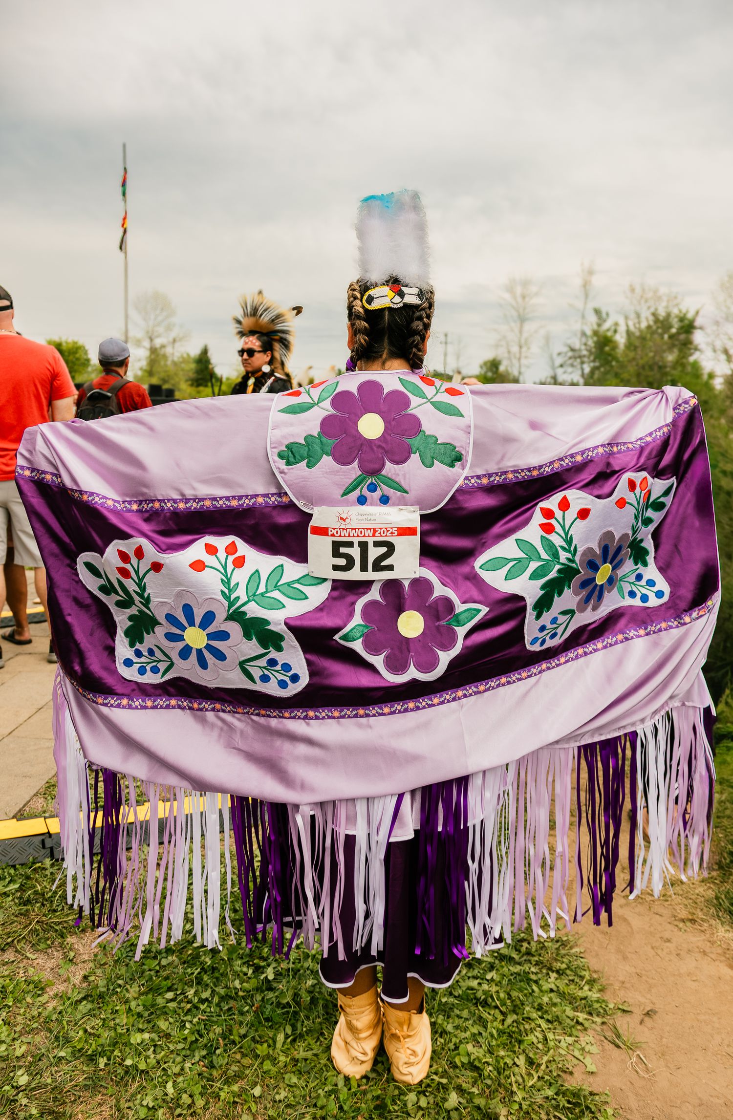 A beautifully decorated purple shawl with floral beadwork and fringe displayed outdoors.