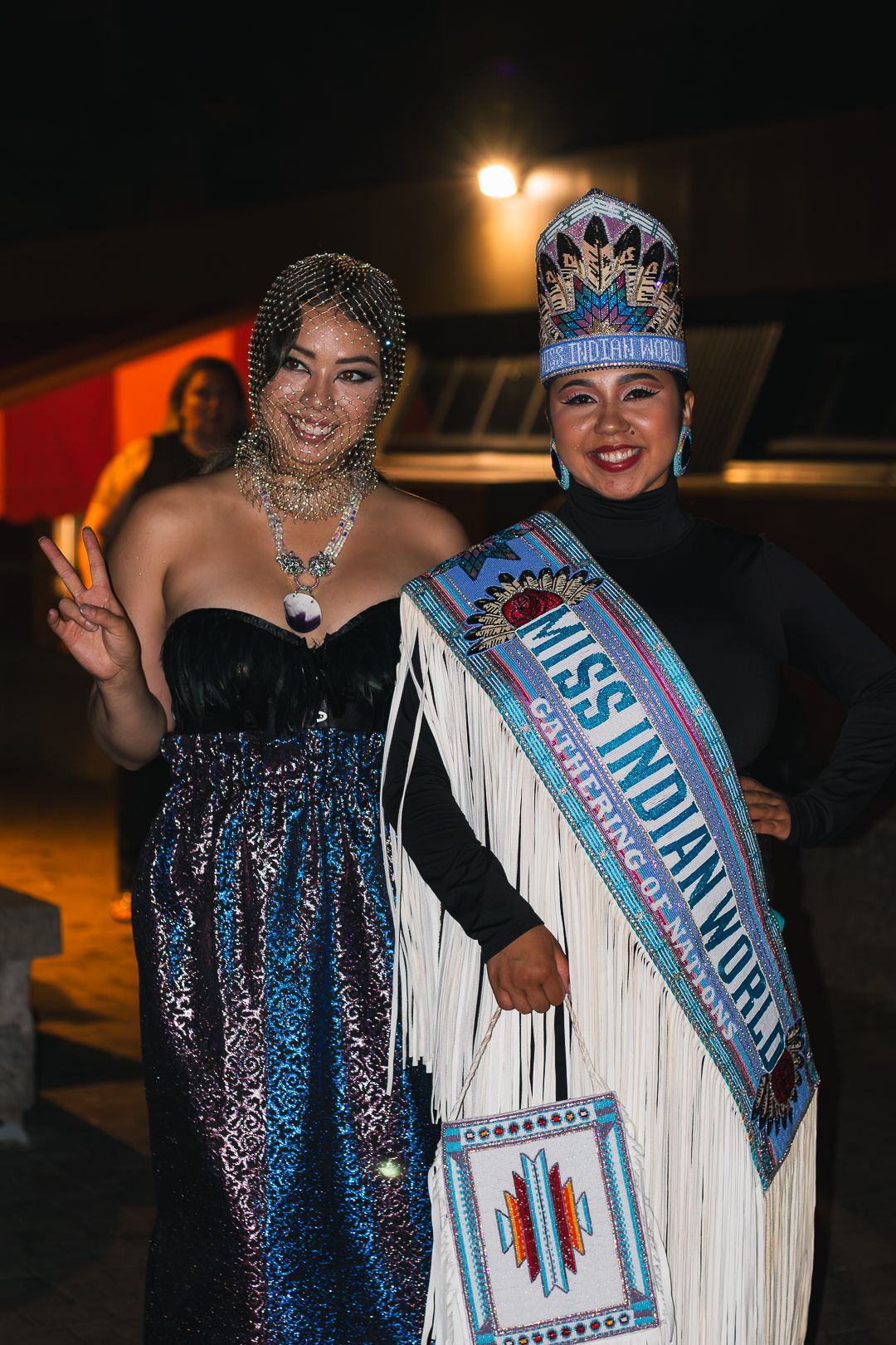 Participants wearing blue and white sashes and formal attire pose at a celebratory event.