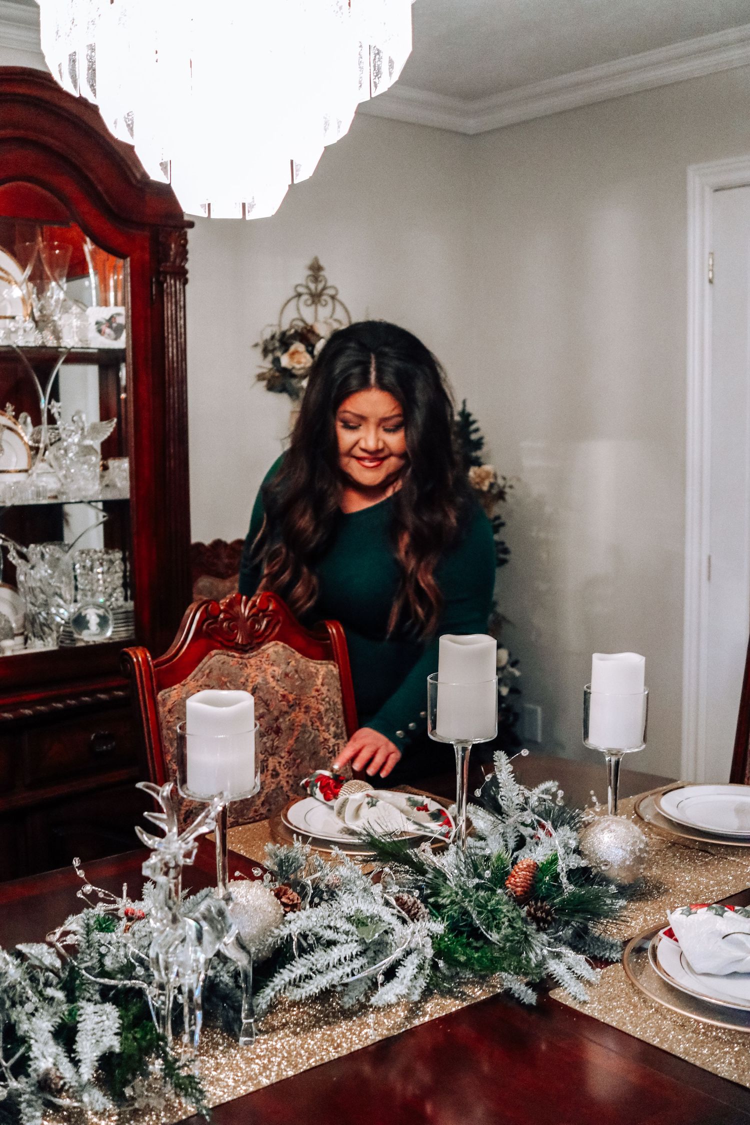 An elegant dining table set with white candles and frosted greenery for Christmas.
