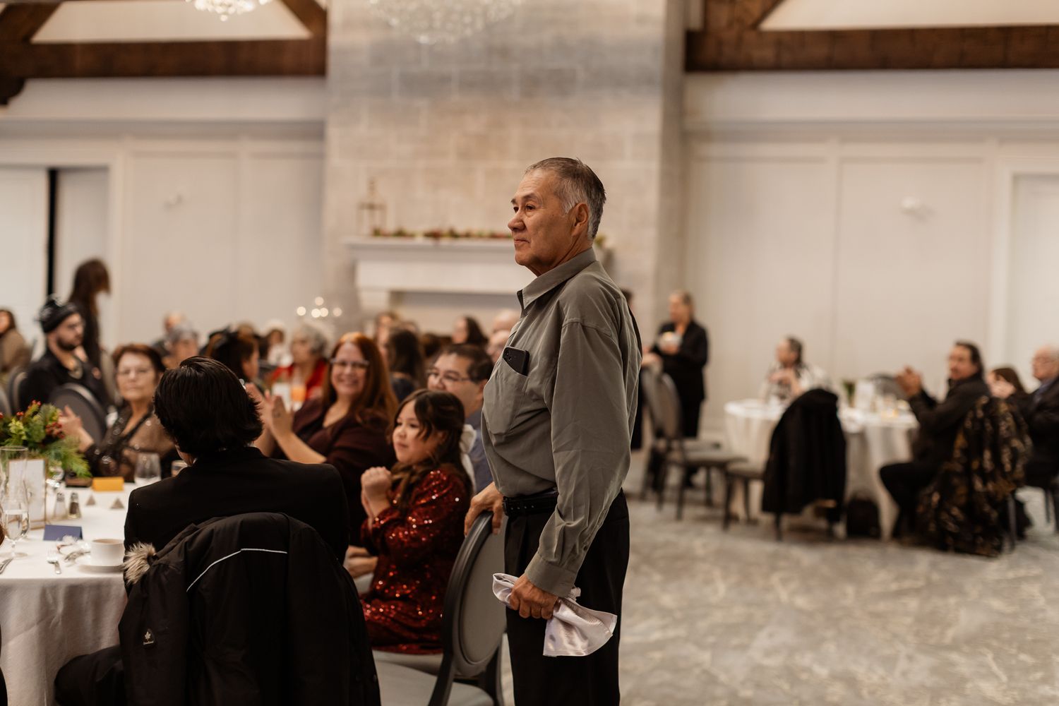 People gathered in a large meeting room with white walls and holiday decorations.