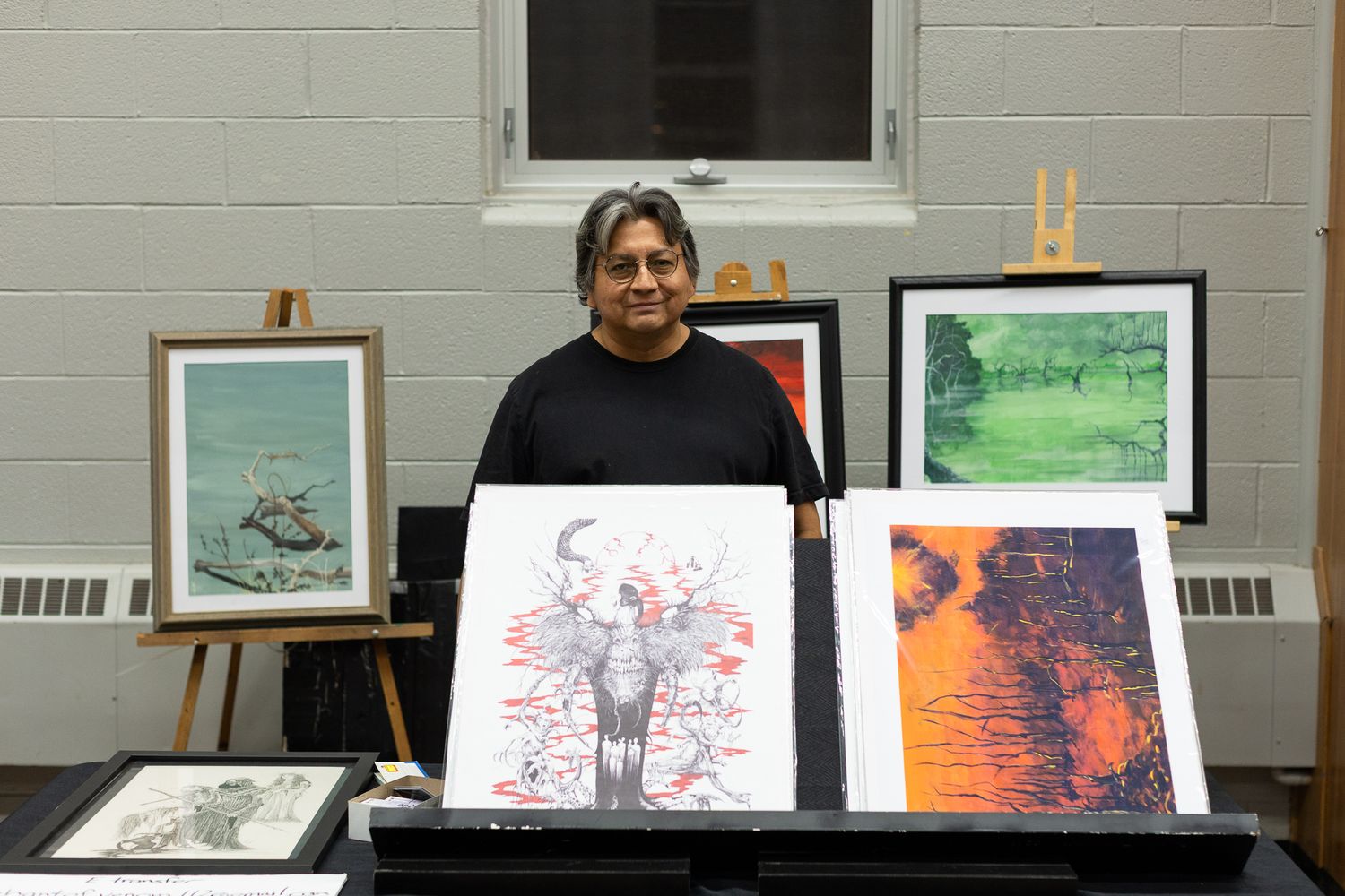 Art gallery wall displaying various framed paintings and artwork in a community space.