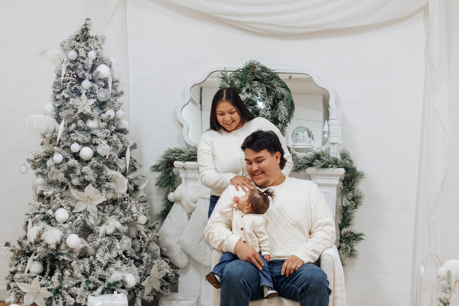 Holiday family photo session with white Christmas trees and elegant decorations.