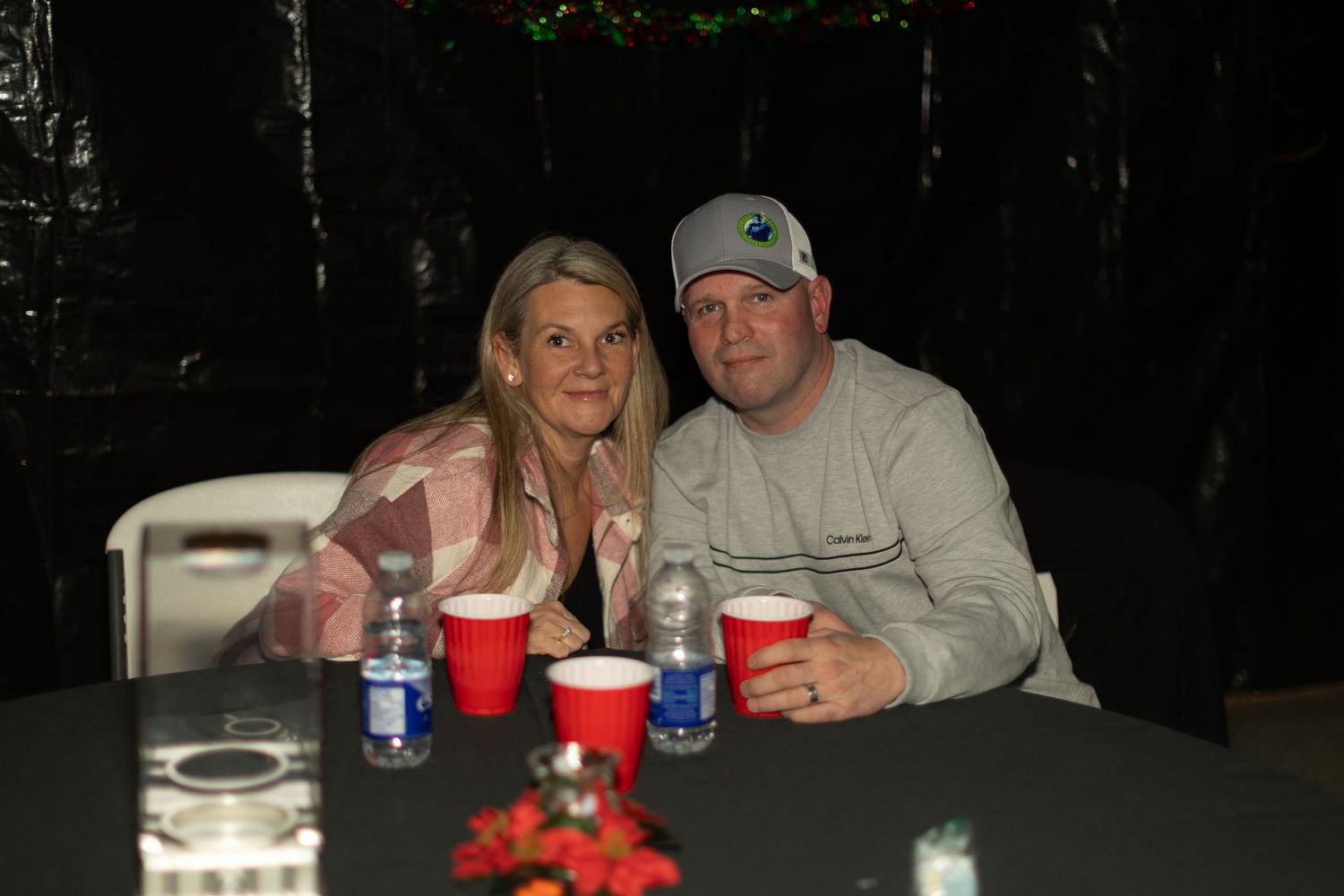 Group gathered around a dark table with red cups and drinks.