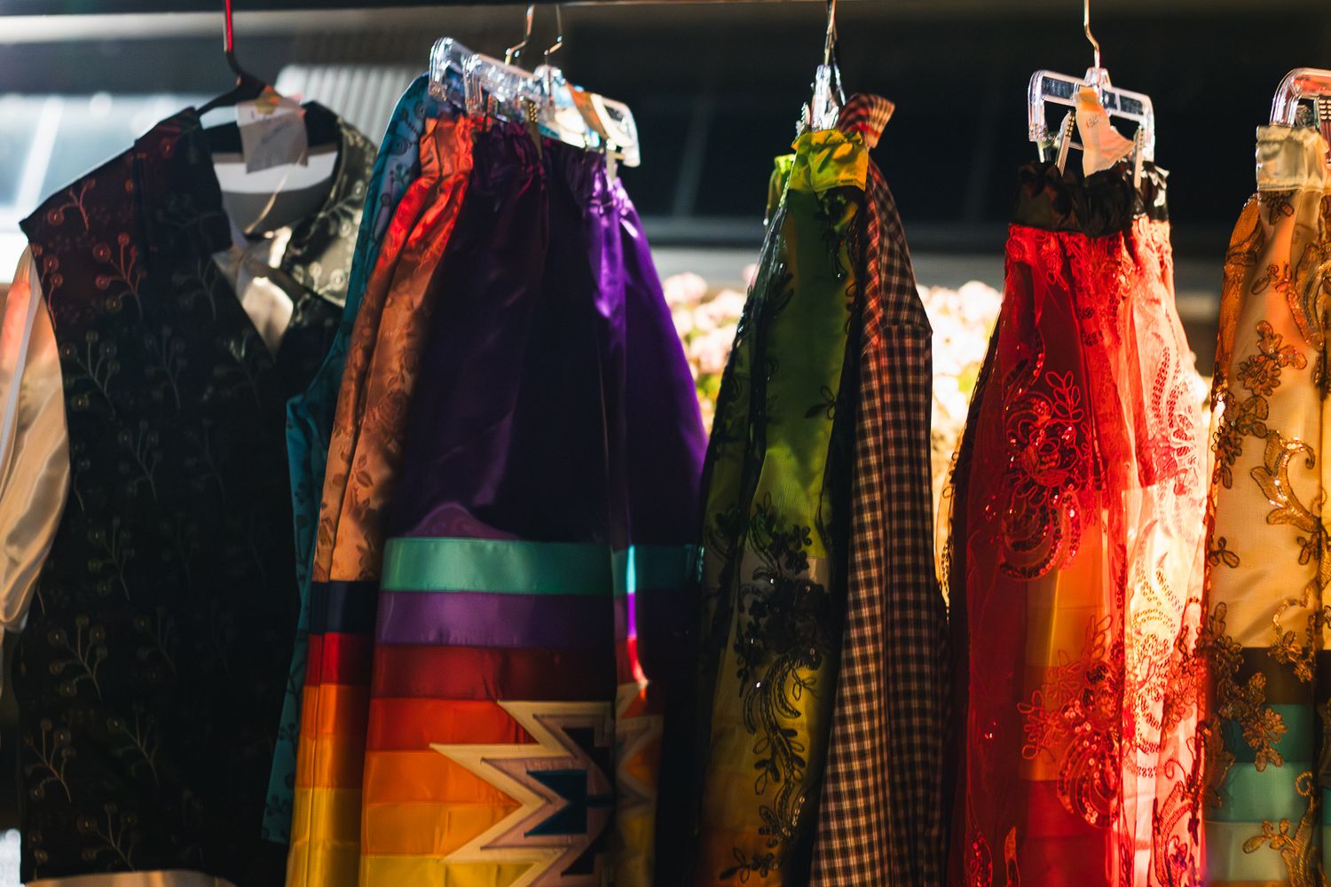 Colorful vintage skirts and garments hanging on a clothing rack, featuring vibrant patterns and rich fabrics.