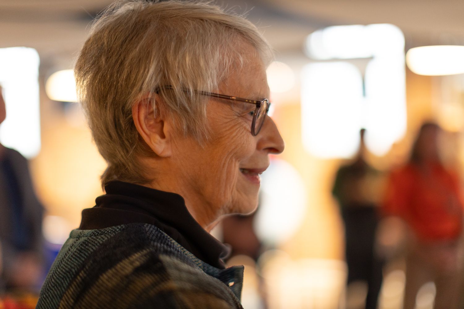 Profile view of a person smiling while attending an indoor event.