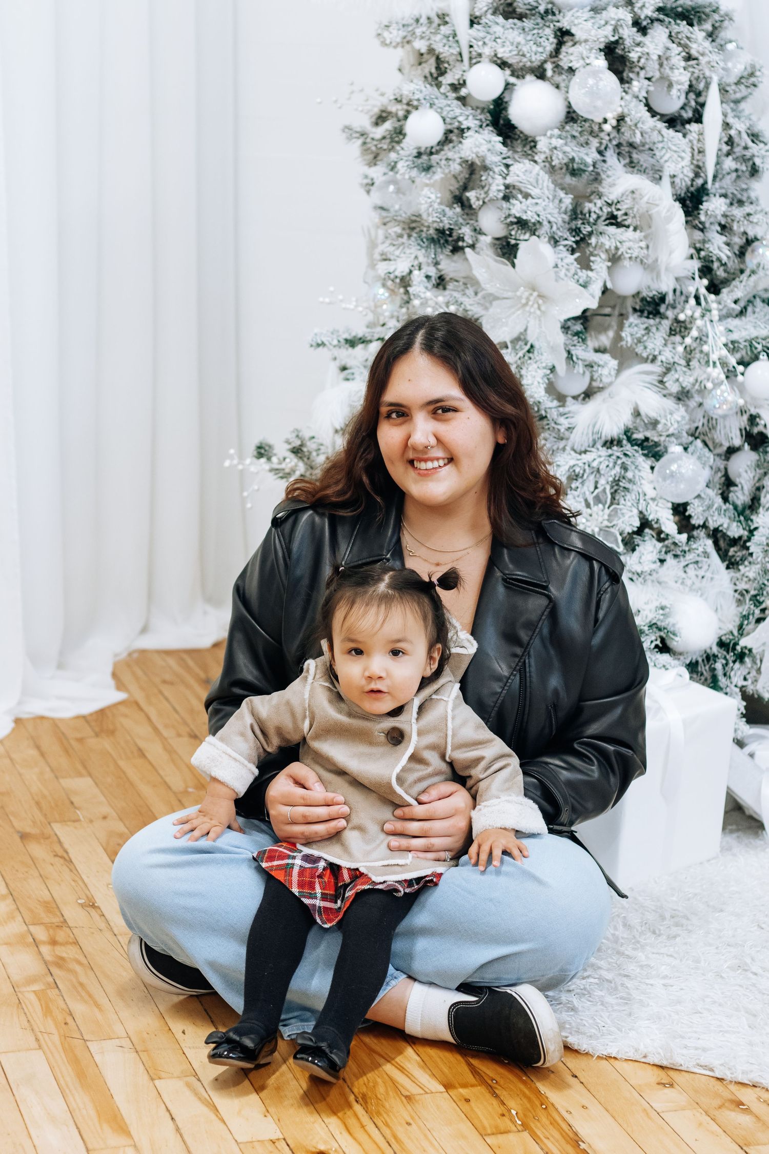 Holiday photoshoot scene with flocked Christmas tree and wooden floor setting.