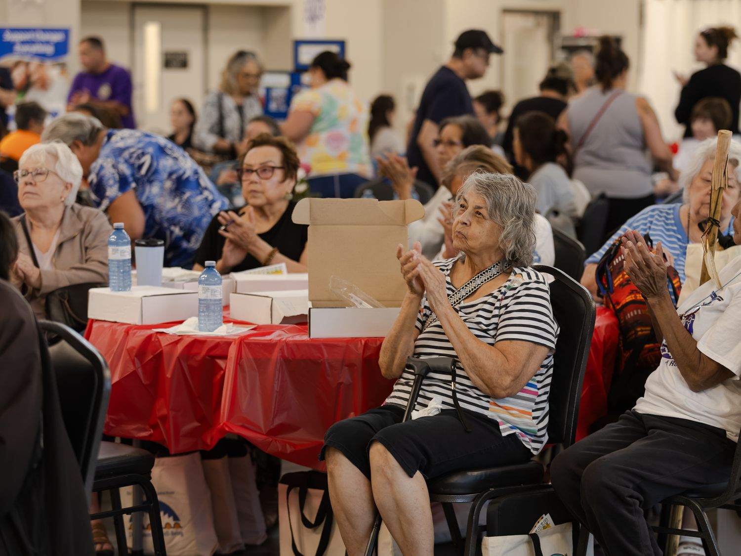 Senior citizens and community members seated at tables during an indoor health fair event.