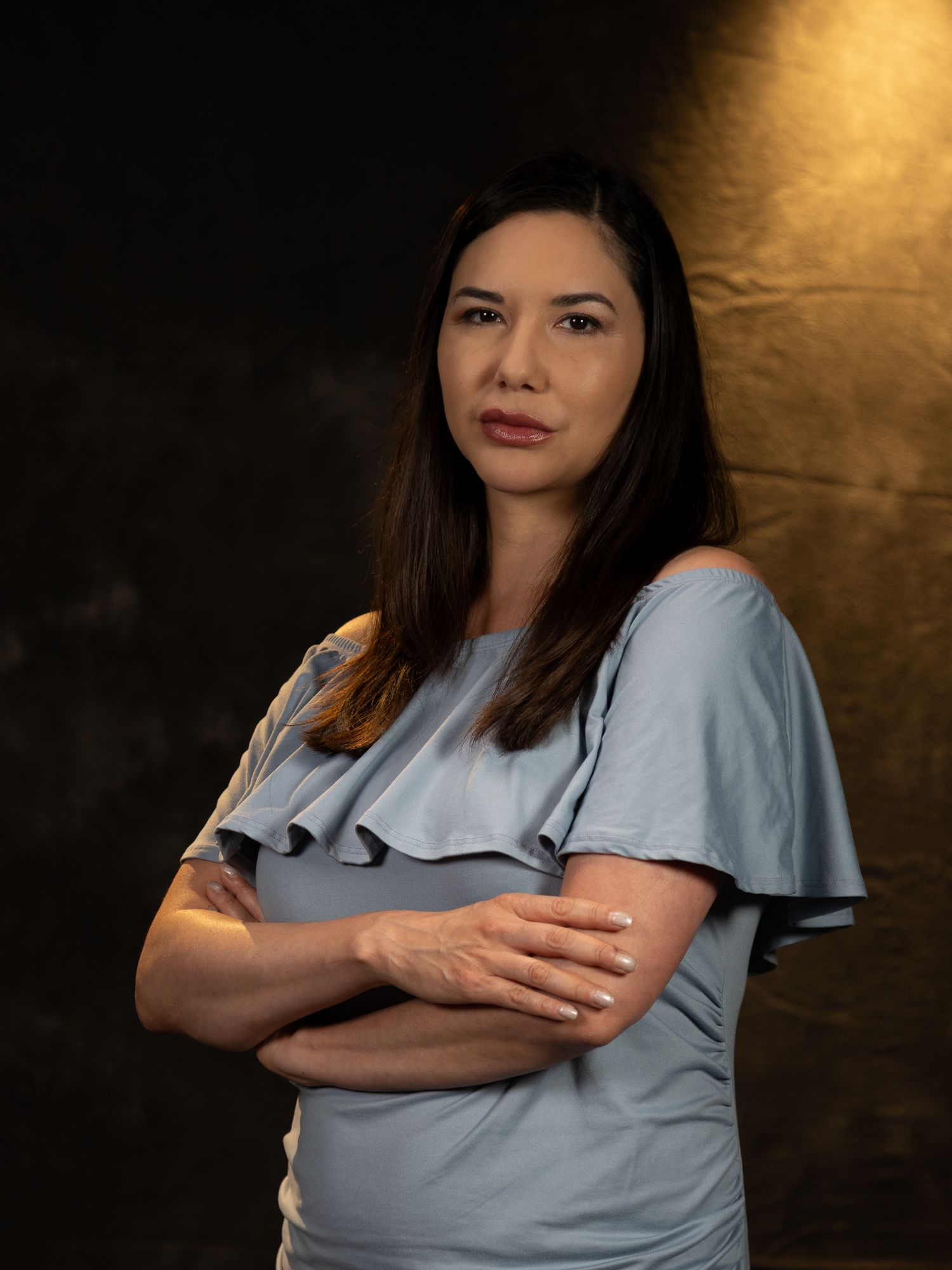 Multiple poses of someone wearing a light blue ruffled top against a dark background.