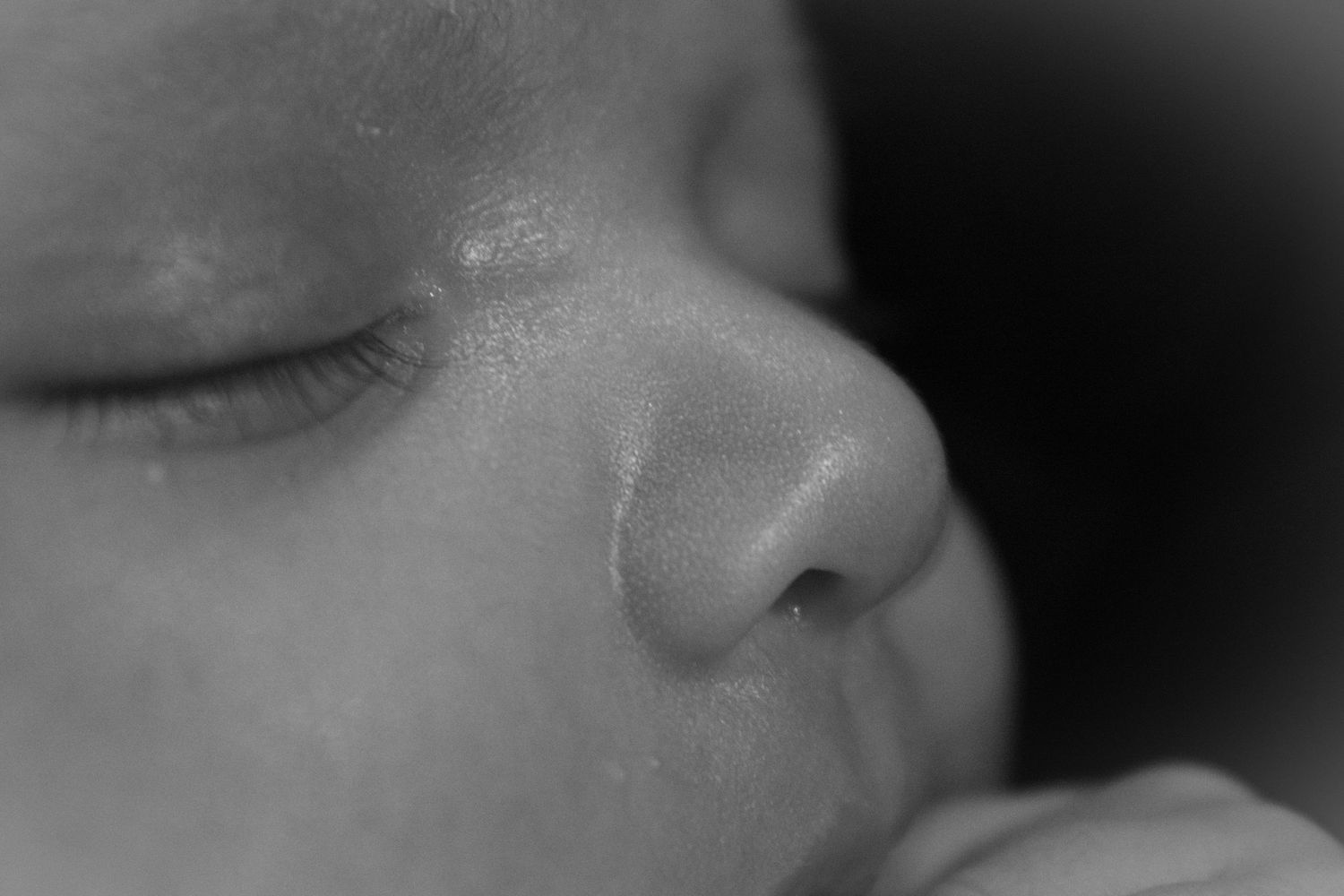 Gentle black and white capture of infant's nose and lips while sleeping.