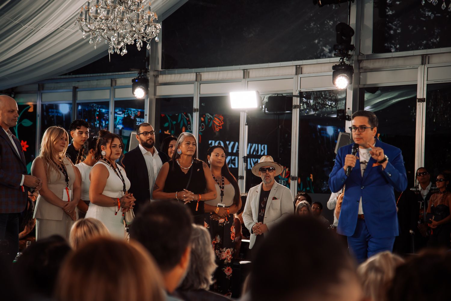 Large crowd gathered under a tent canopy at an outdoor event.