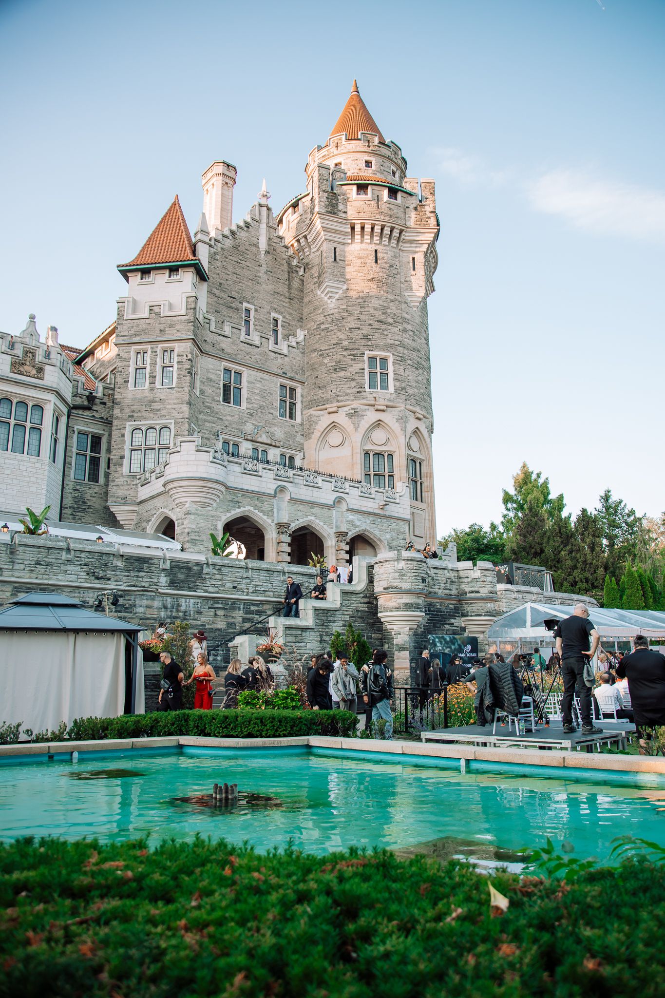 Elegant castle venue with turrets and a fountain pool surrounded by guests at an outdoor evening event.