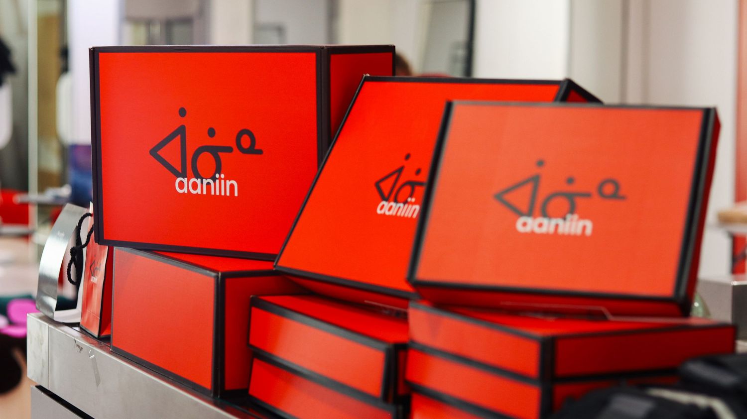 Stack of red Aaniin branded gift boxes displayed on a shelf in a retail store setting.