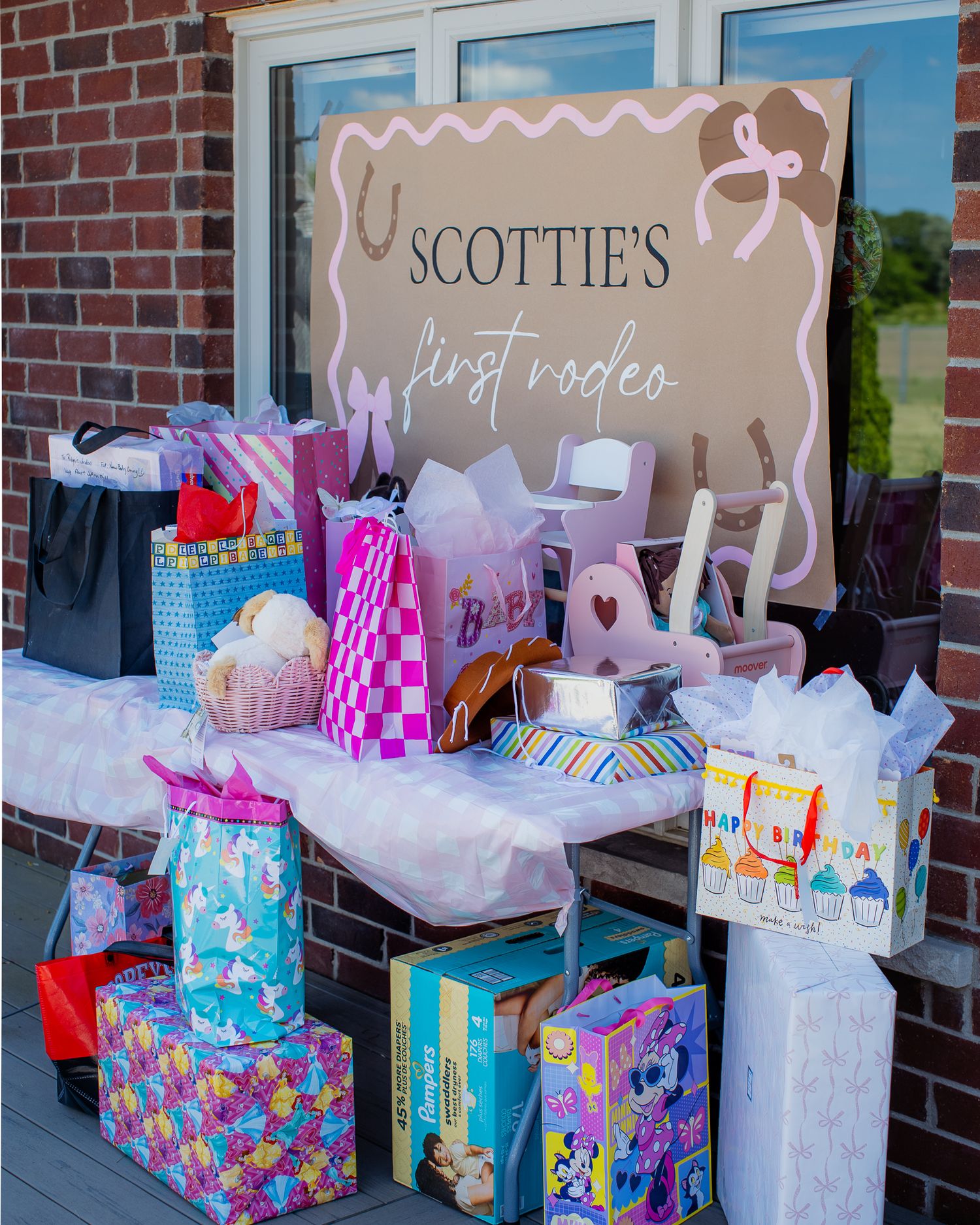 A colorful gift table display for Scottie's First Rodeo first birthday party with wrapped presents and gift bags.