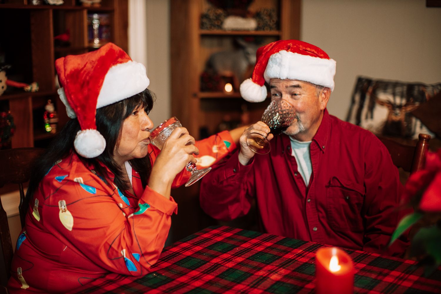 Festive dinner party with people in Santa hats and red attire around a decorated table.
