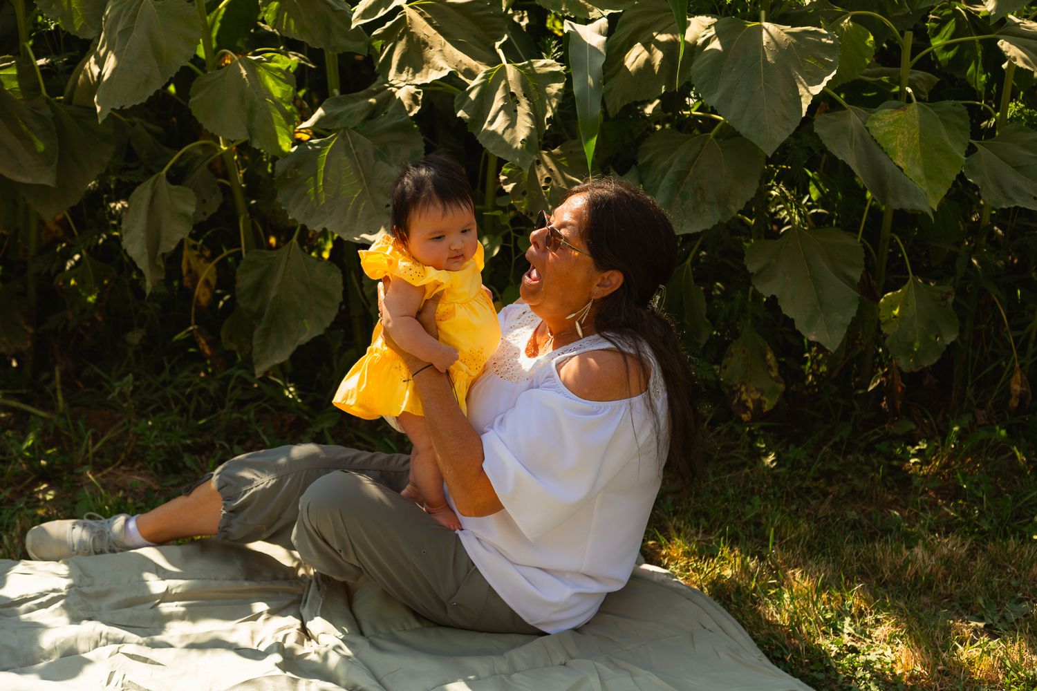 A couple shares tender moments together while sitting under lush green foliage in a garden setting.