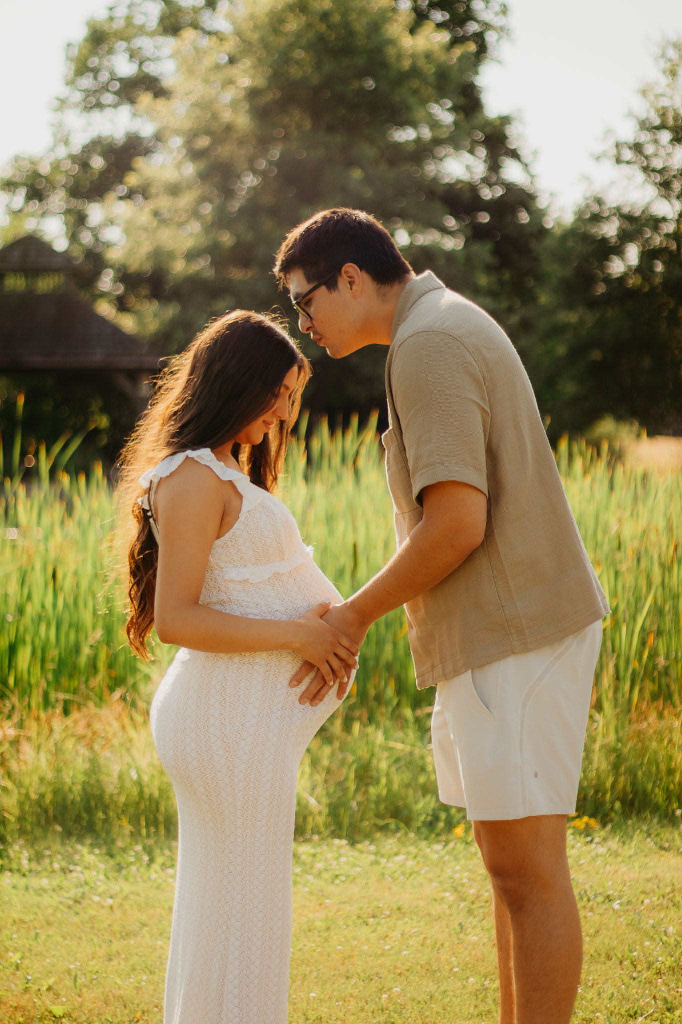 Golden hour maternity session capturing intimate moments between expectant parents outdoors.