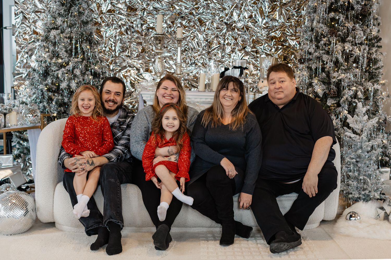 Casual winter family portrait against a decorated Christmas tree background.