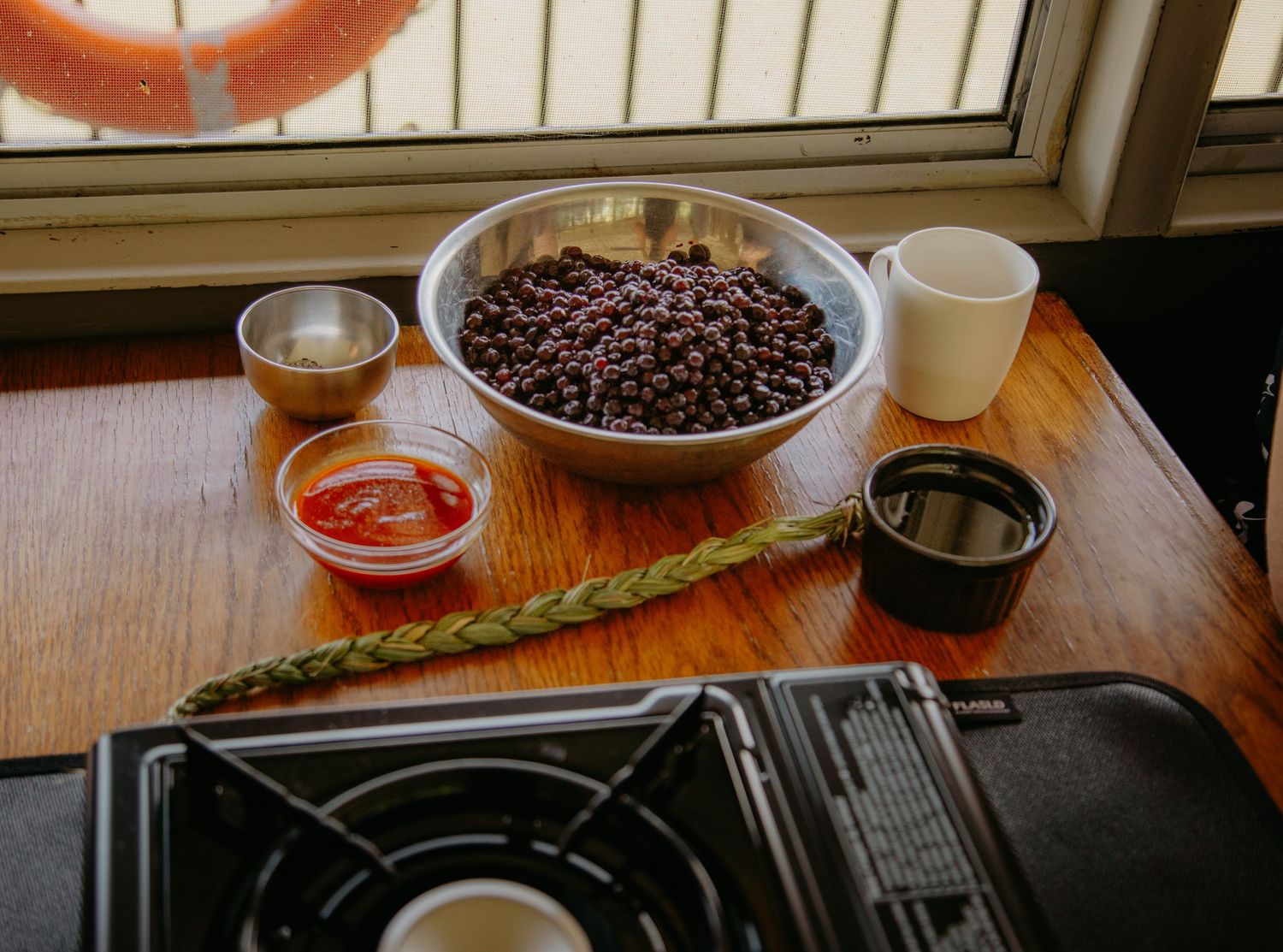 Coffee beans and brewing equipment arranged on a wooden counter near a window.