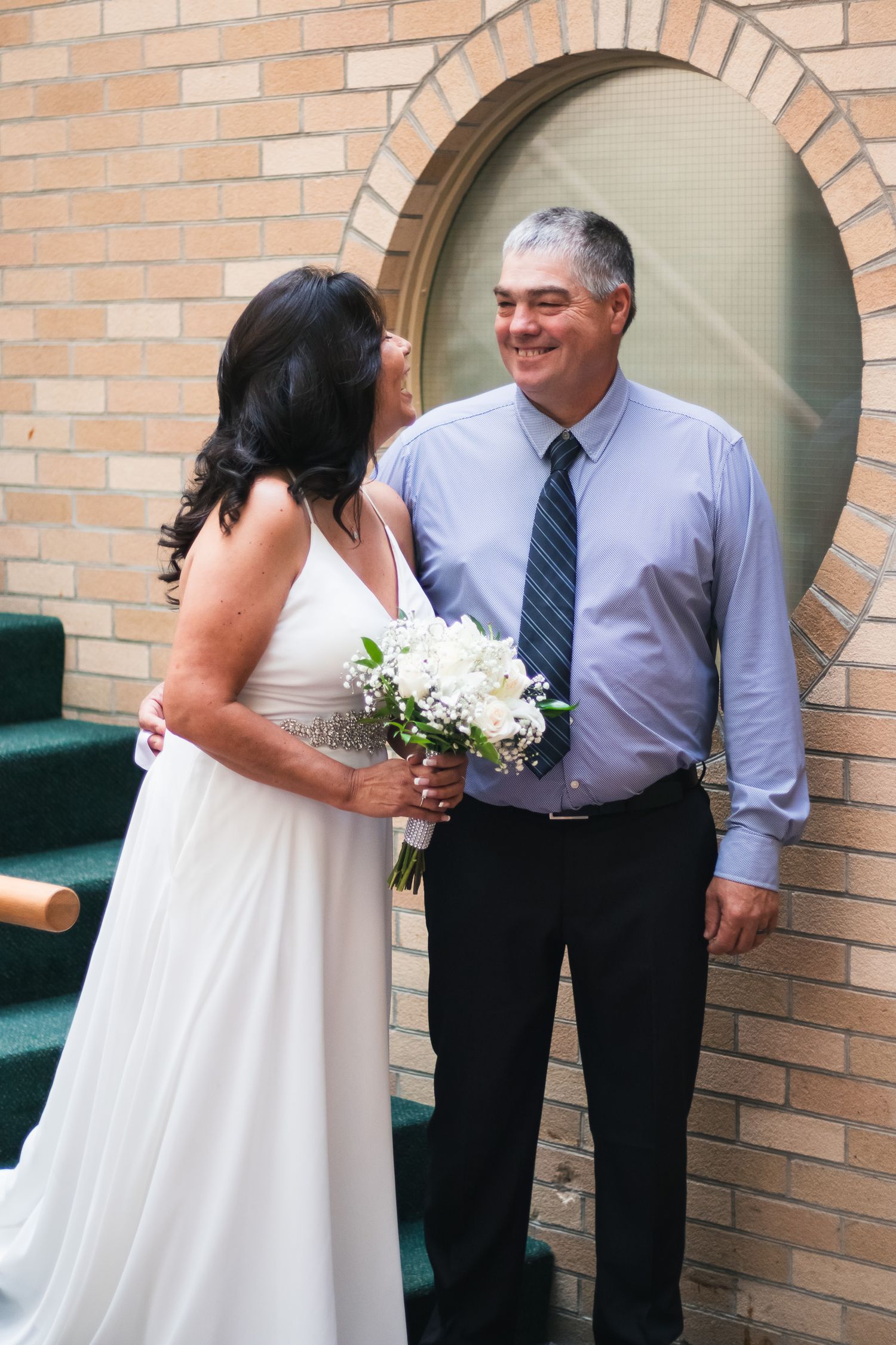 Wedding celebration candid moments outside brick building.