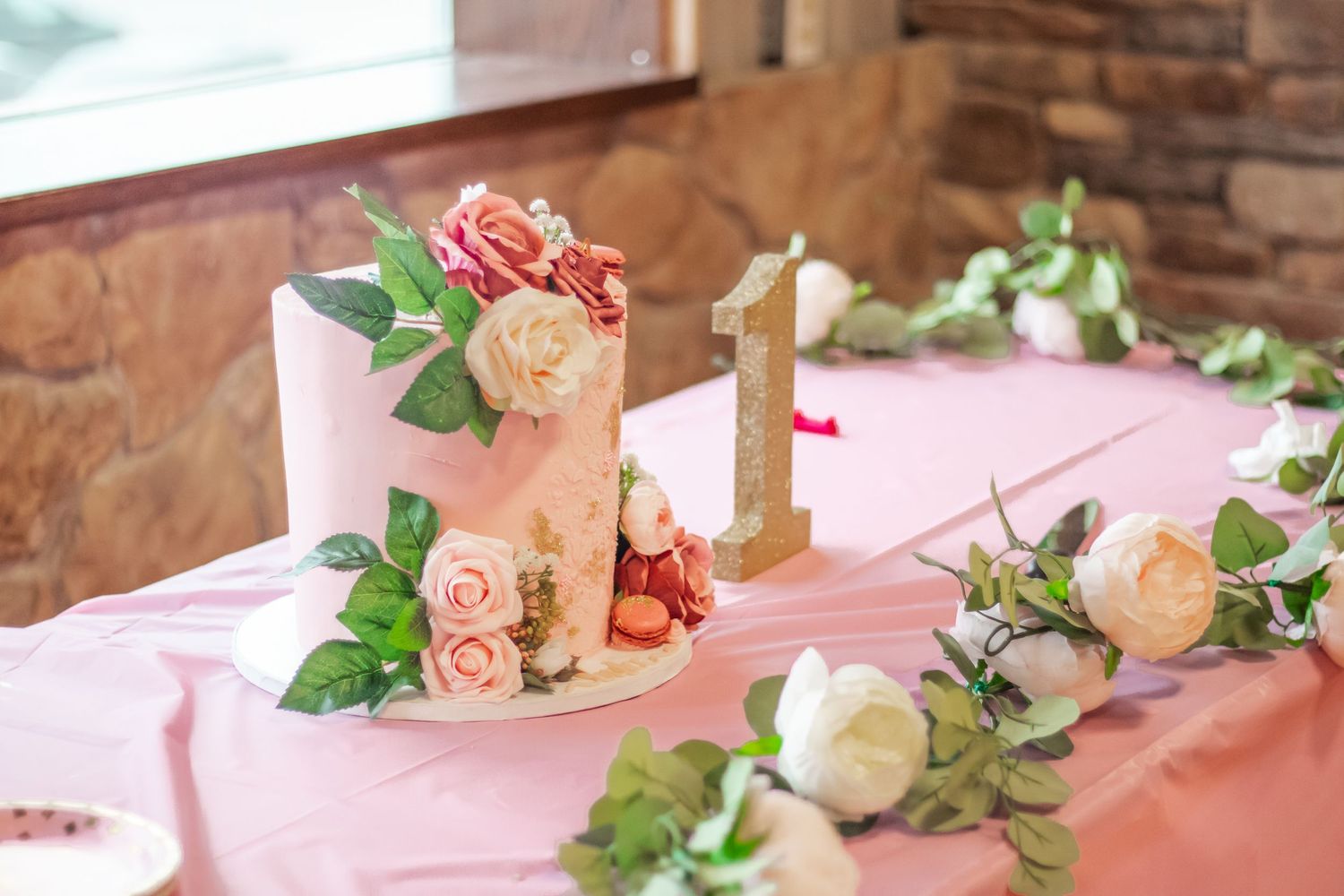 Elegant floral arrangement with roses and greenery on a pink tablecloth.