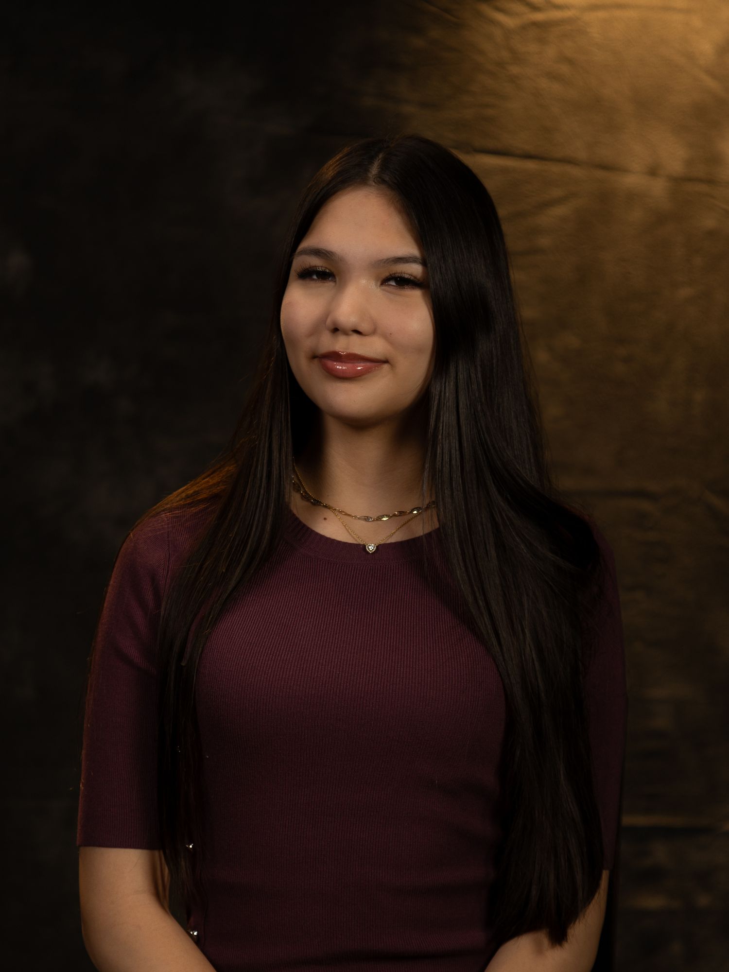 Portrait series featuring someone in a burgundy top against a warmly lit dark background.