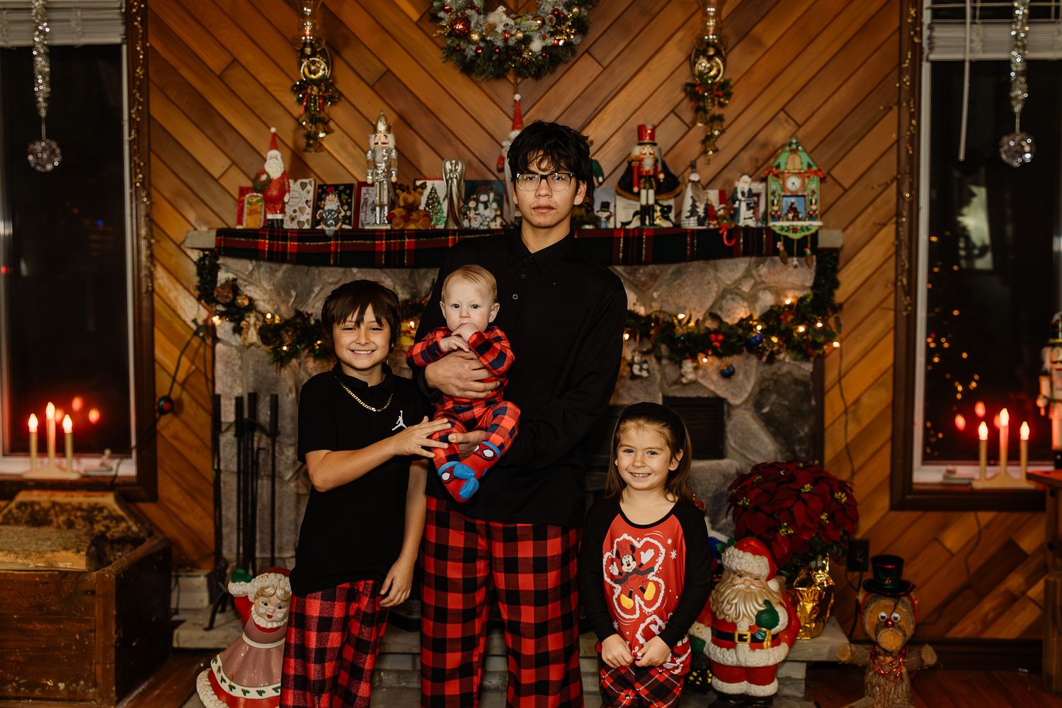 Christmas portrait session with decorated tree and red candles in rustic wood-paneled room.